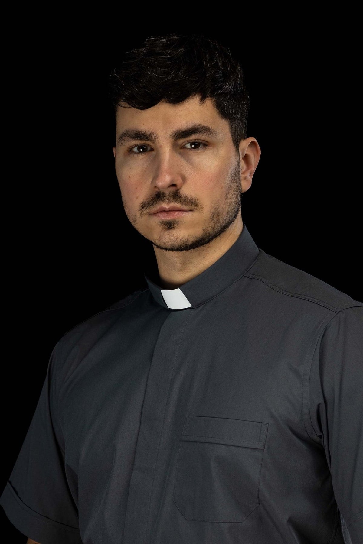 Dark gray clergy shirt close-up with clerical collar and chest pocket