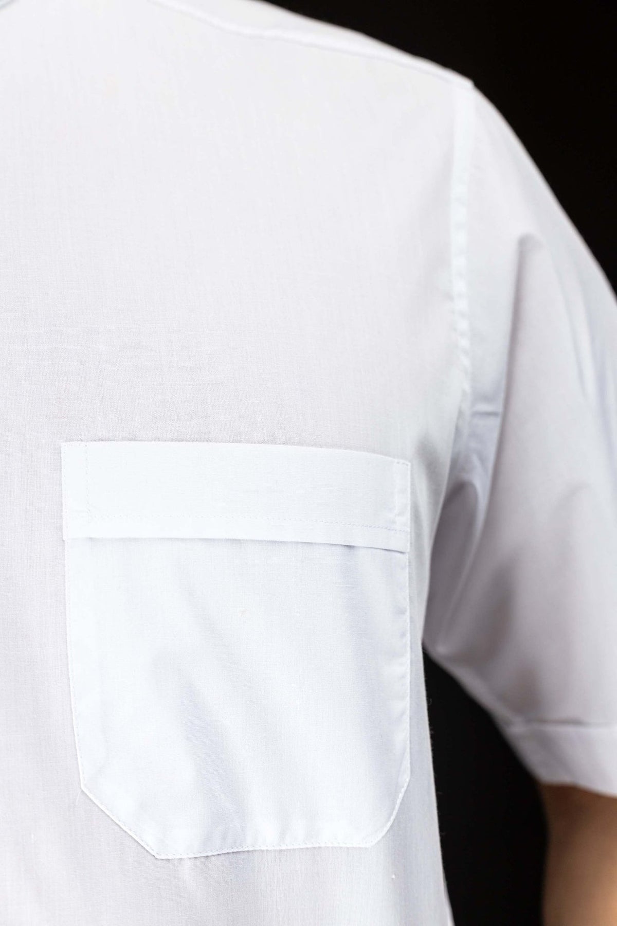 White clergy shirt close-up showing the chest pocket and short sleeve