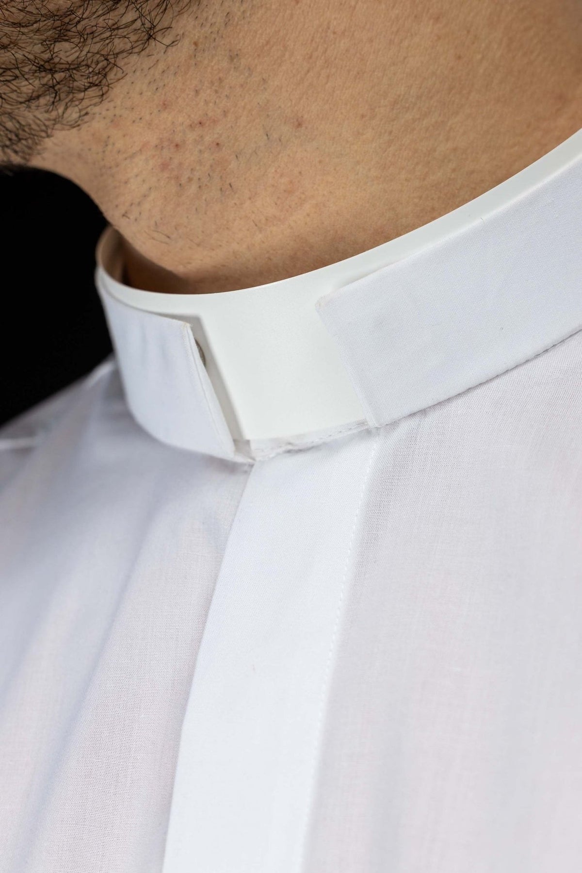 White clergy shirt close-up showing the clerical collar and front placket