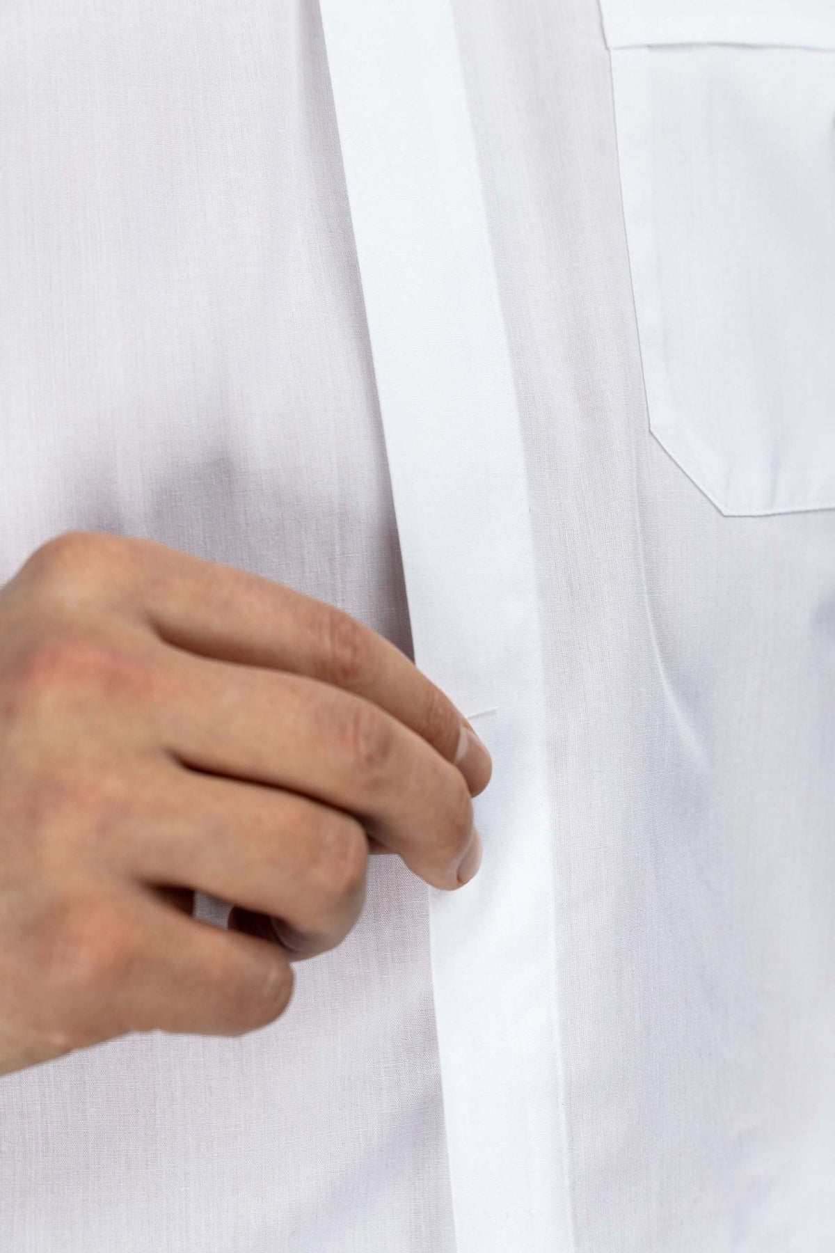 White clergy shirt close-up showing the buttoned long sleeve cuff
