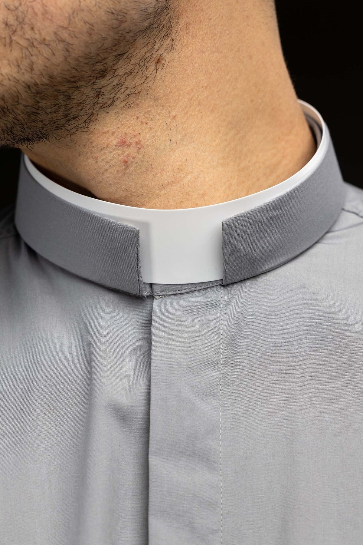 Clergy shirt close-up showing gray fabric and white clerical collar