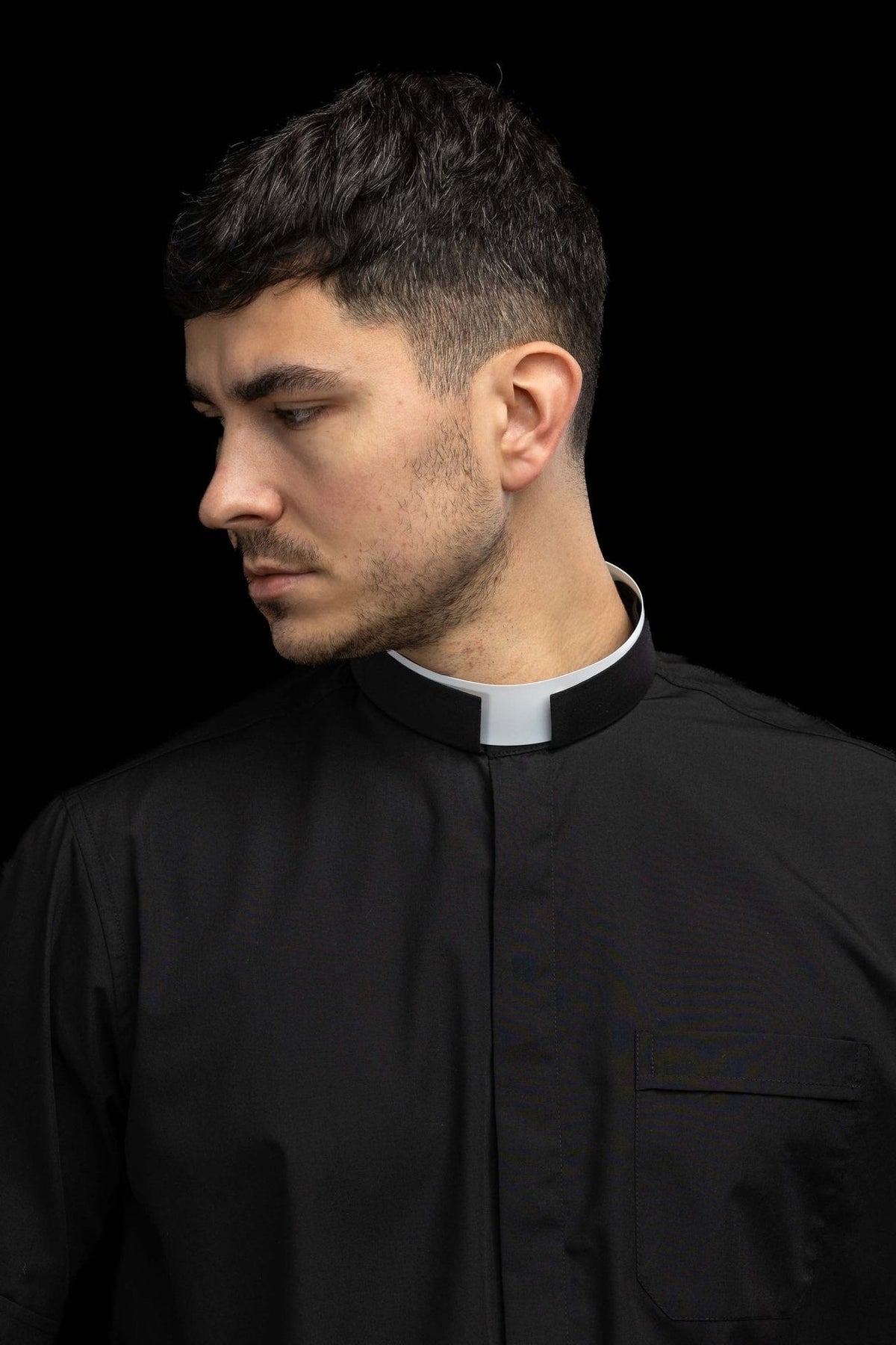 Black clergy shirt worn from the side with Roman collar