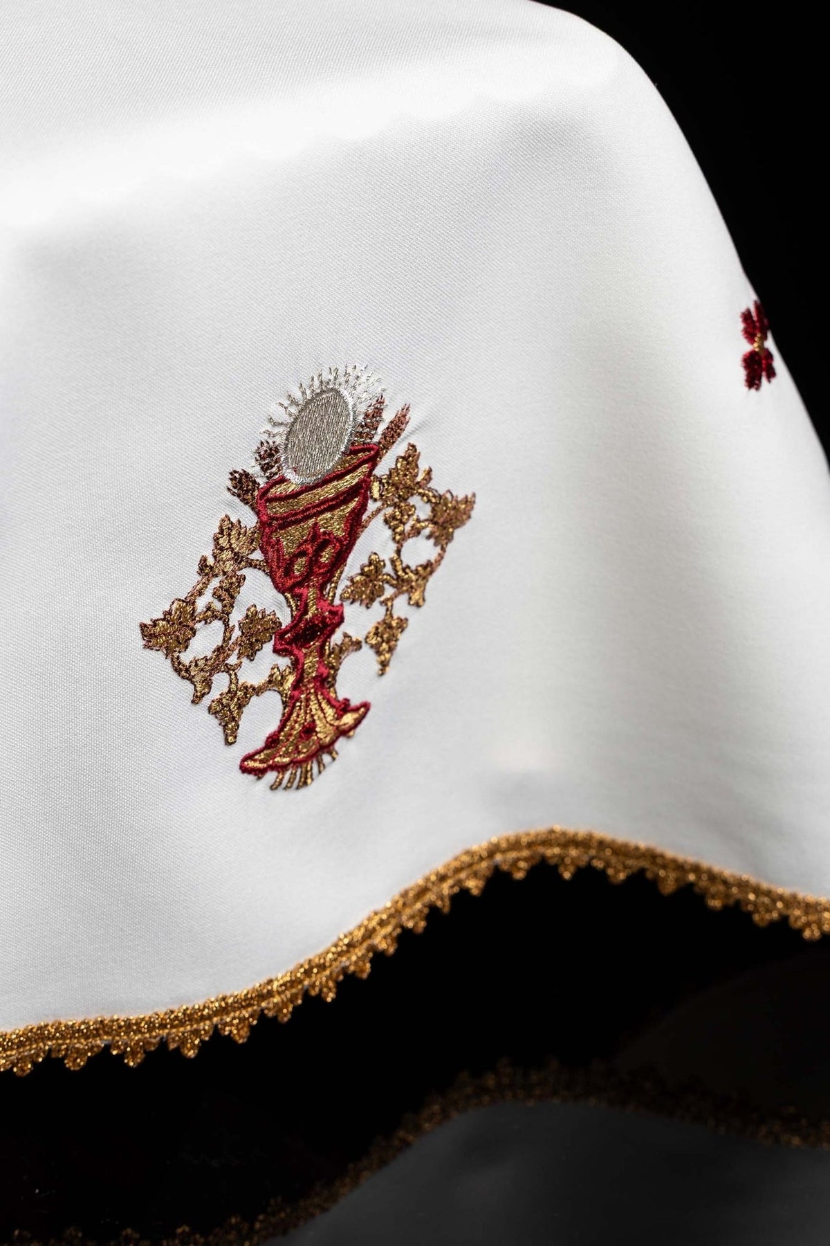White chalice veil close-up showing embroidered communion chalice and gold trim