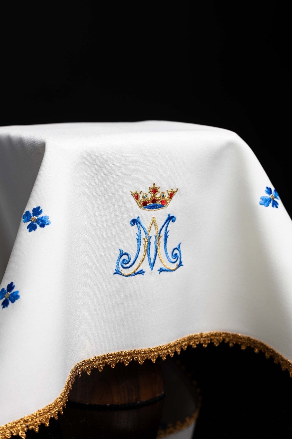 Chalice veil detail showing white fabric, Marian embroidery, blue flowers and gold edging