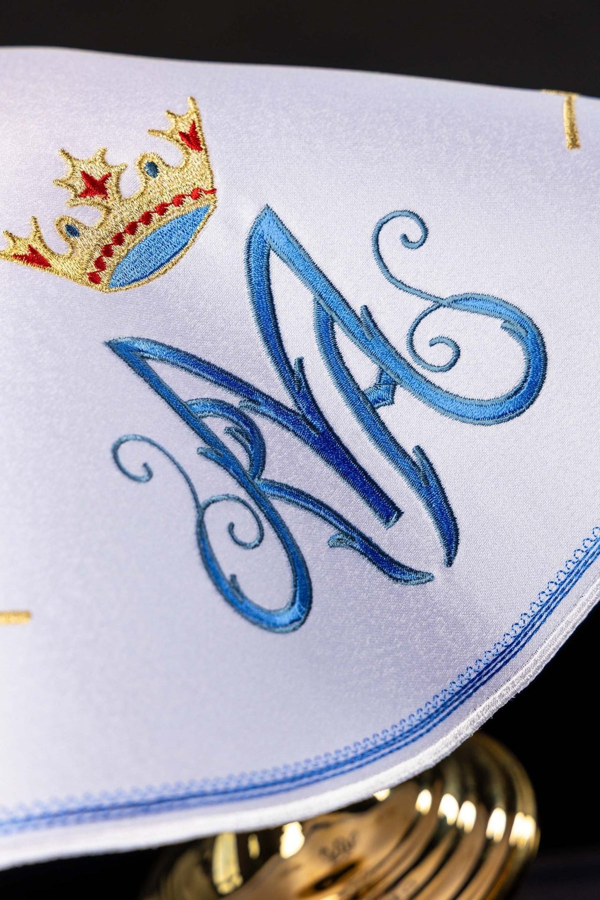 Ciborium veil close-up showing embroidered light blue Marian monogram and gold crown