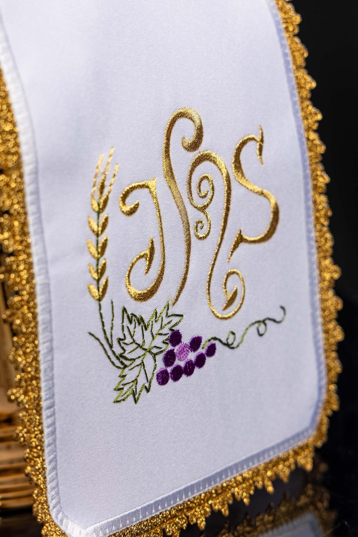 Ciborium veil close-up showing colorful IHS, grapes and wheat embroidery on white fabric