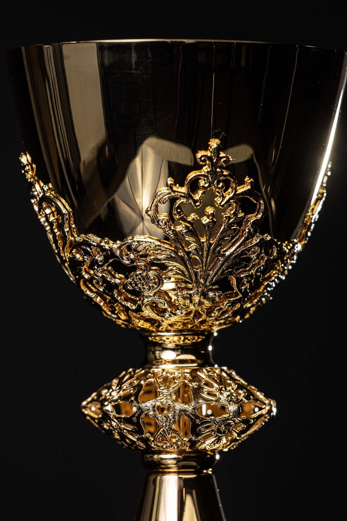 Gold-plated brass chalice close-up showing botanical ornaments on the cup and ornate stem