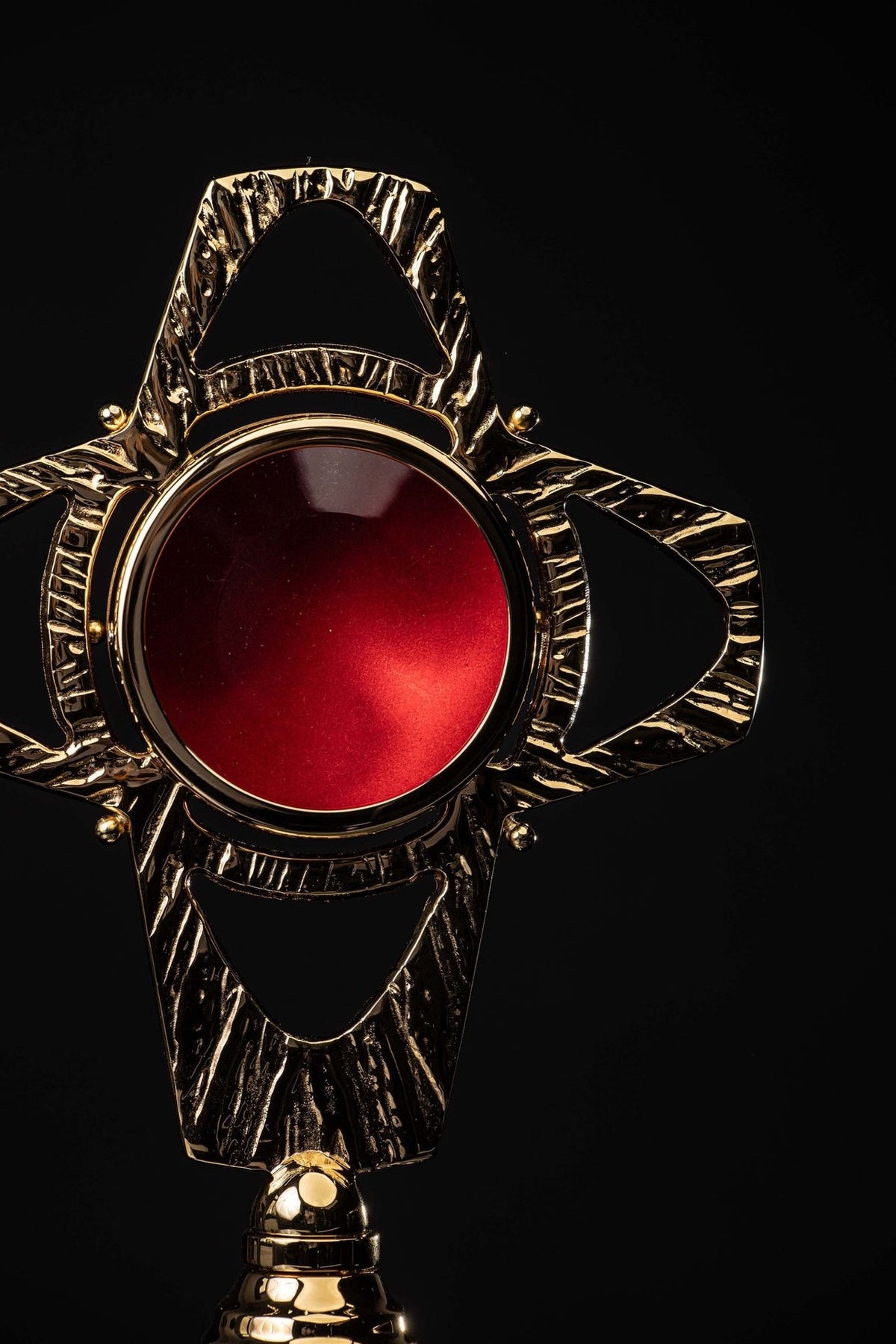 Brass reliquary close-up showing the red center and textured radial frame