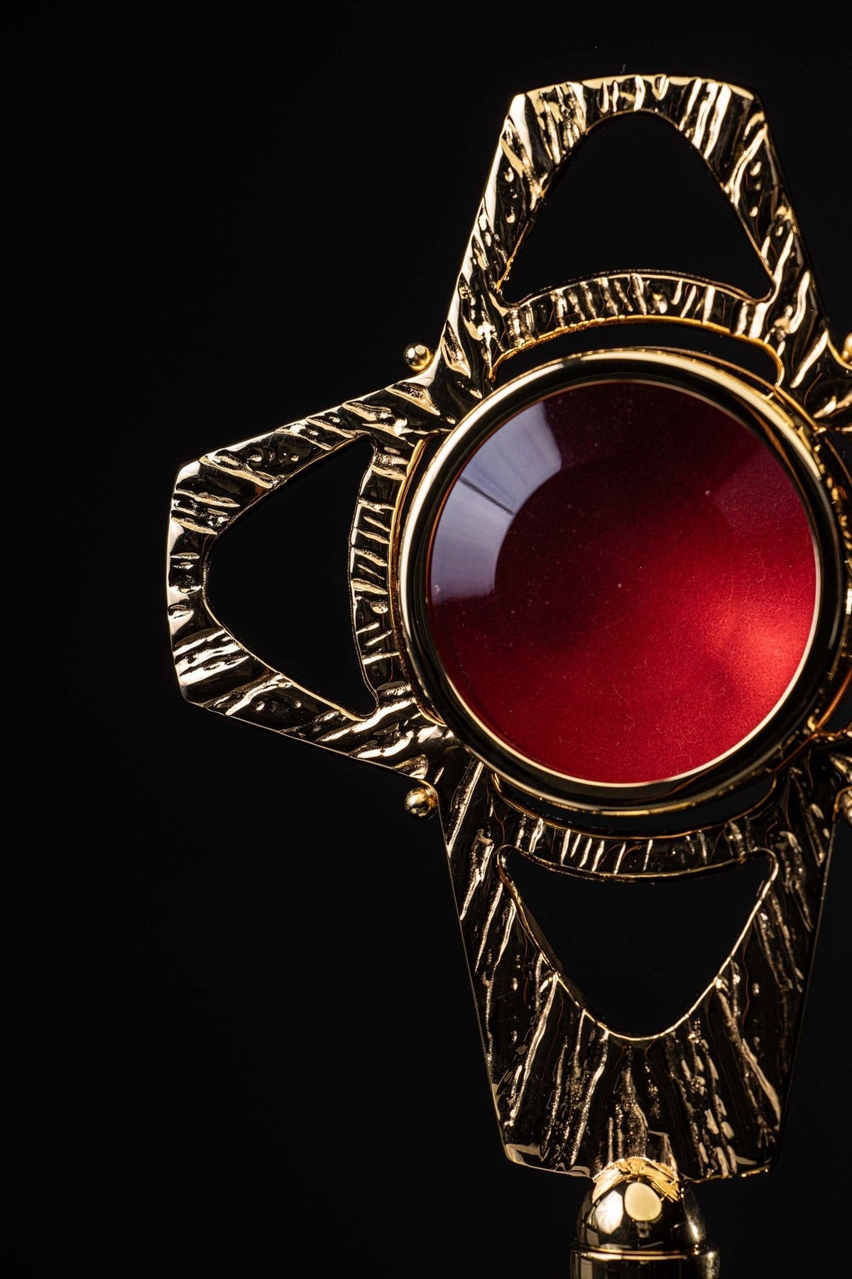 Brass reliquary angled close-up highlighting the red center and upper frame