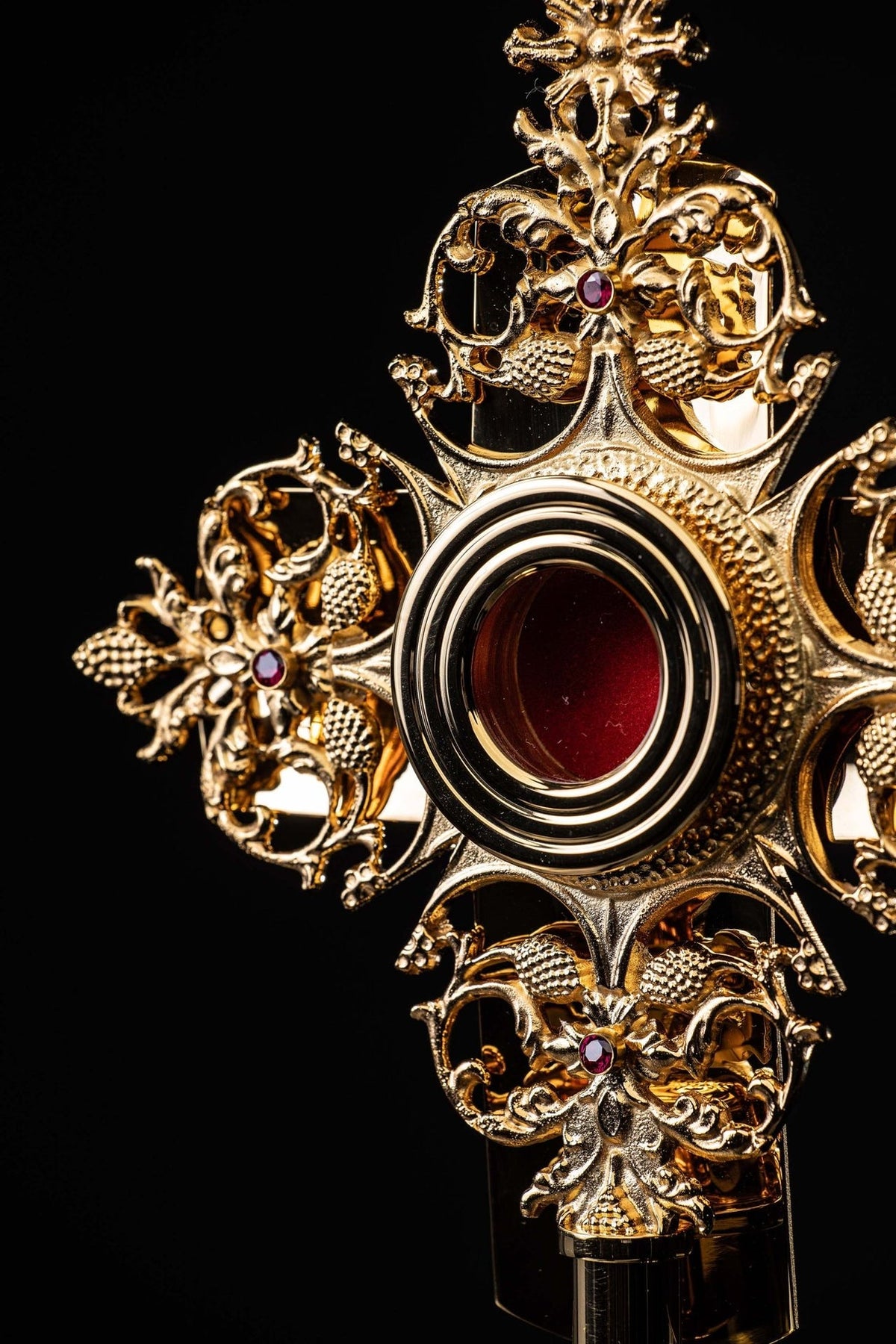Brass reliquary detail showing circular red center and raised gilded floral scrollwork
