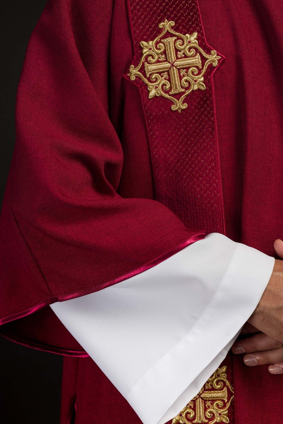 Dalmatic close-up showing red velvet fabric, gold cross embroidery and trim