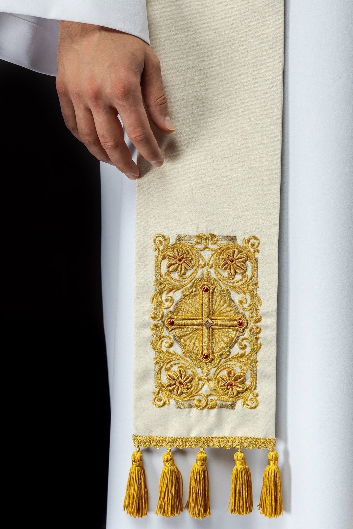Embroidered priest stole close-up showing gold cross, floral motifs, red stones and tassels