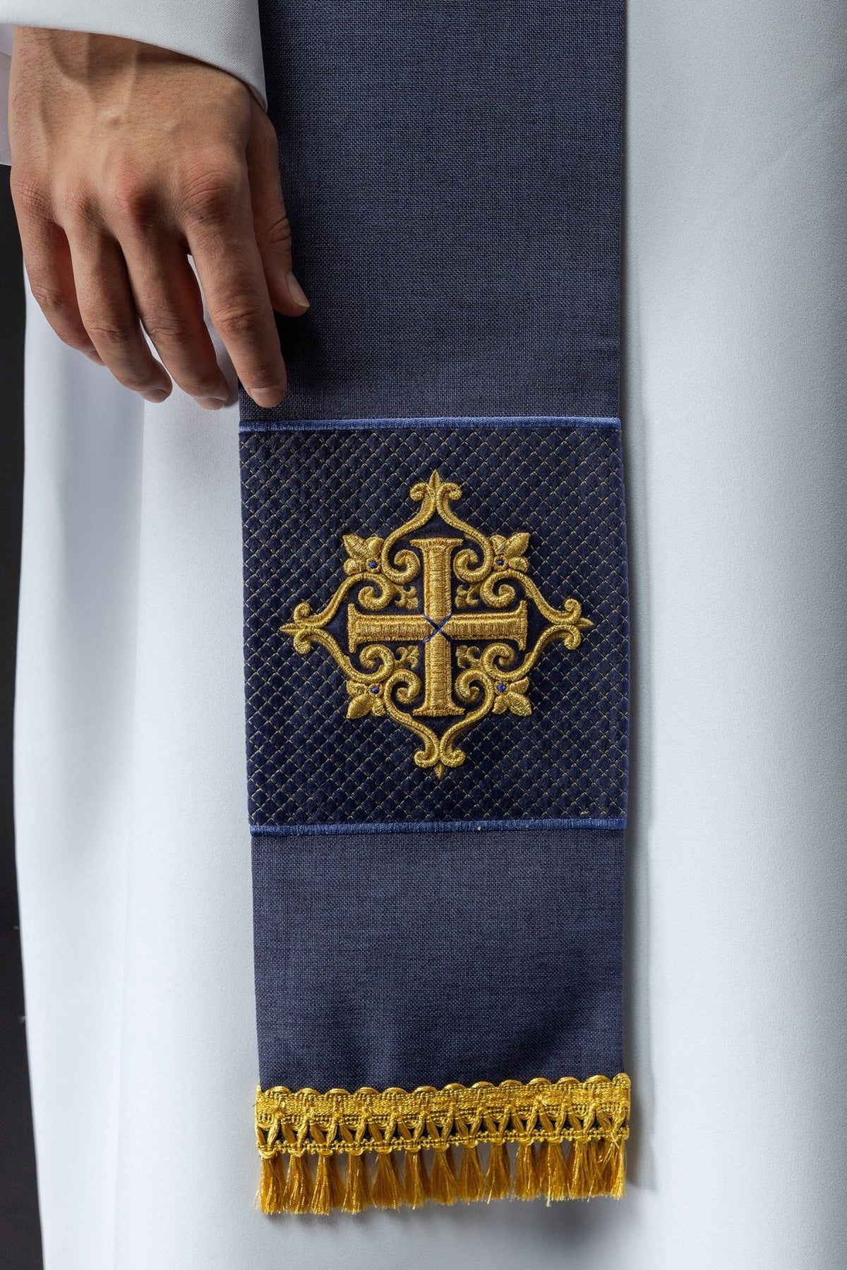 Purple velvet stole close-up showing embroidered gold cross and fringe