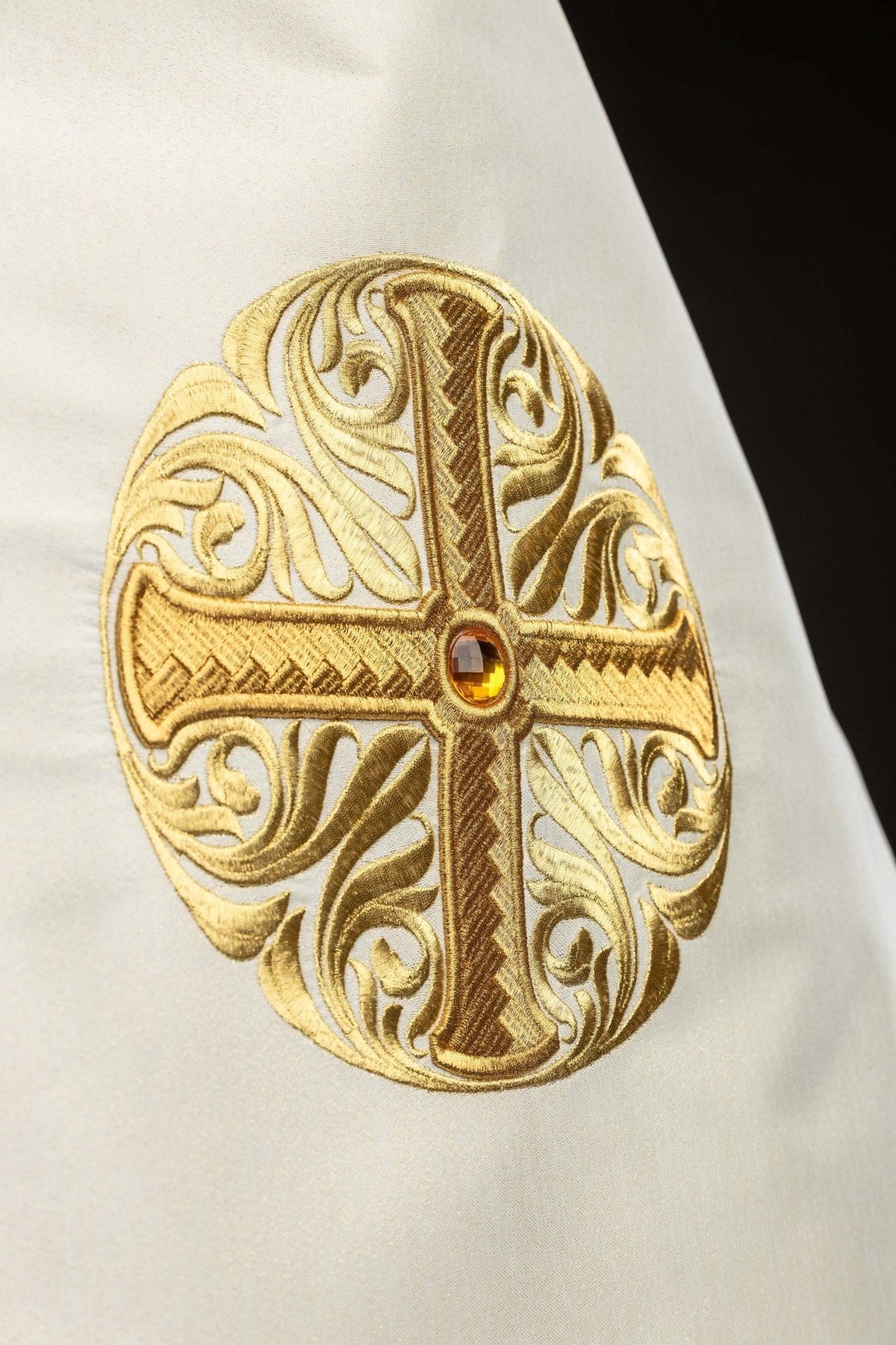Humeral veil close-up showing embroidered gold cross with decorative stone