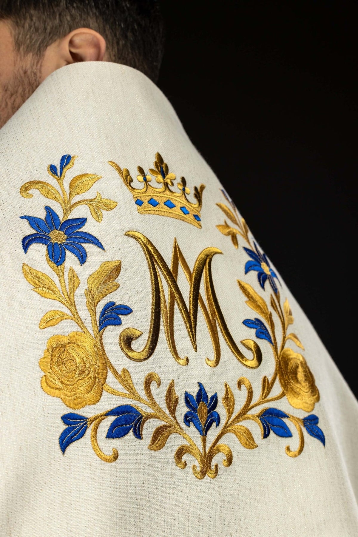 Humeral veil close-up showing gold Marian symbol, crown and blue floral embroidery
