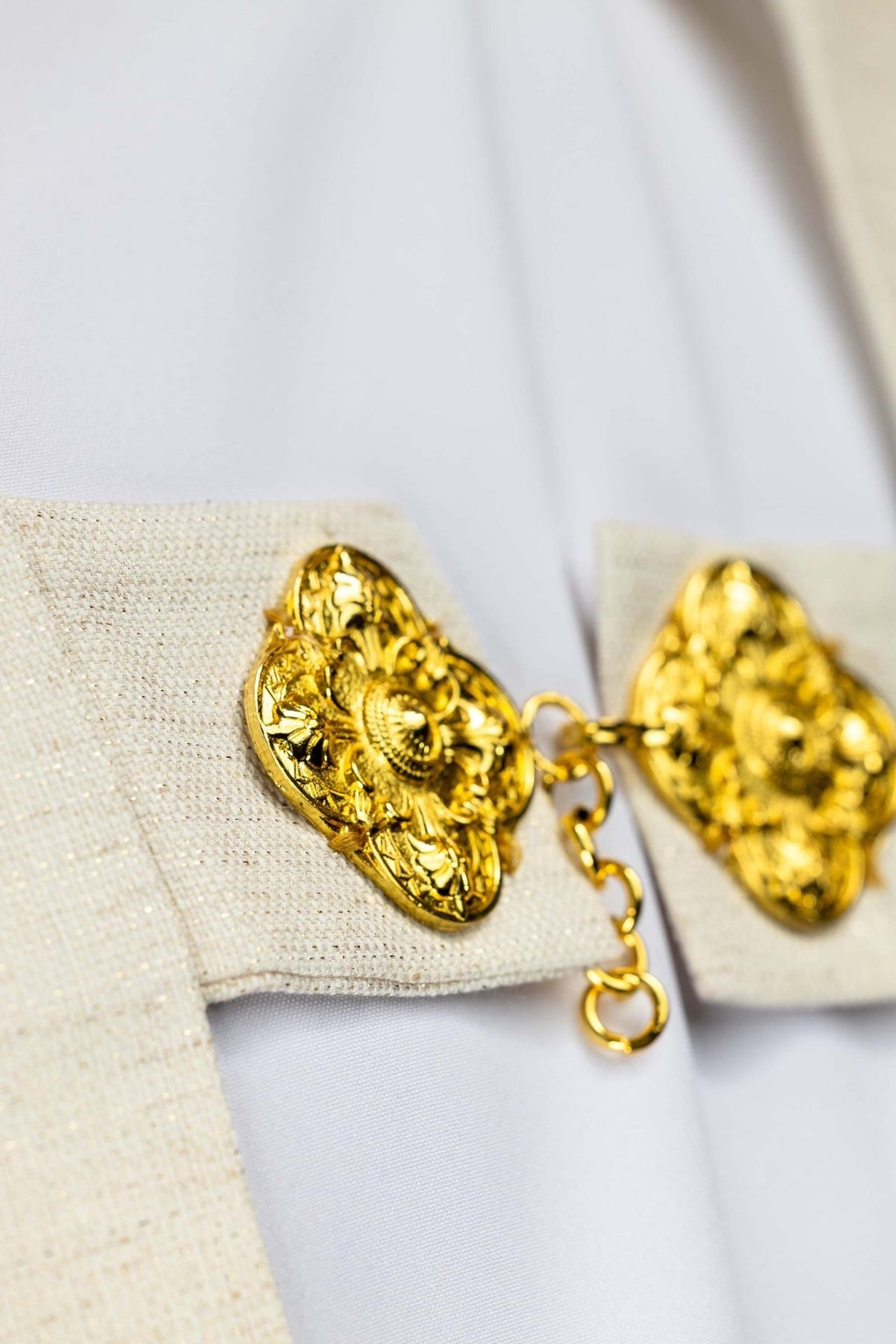 Humeral veil close-up of its gold clasp on ecru fabric