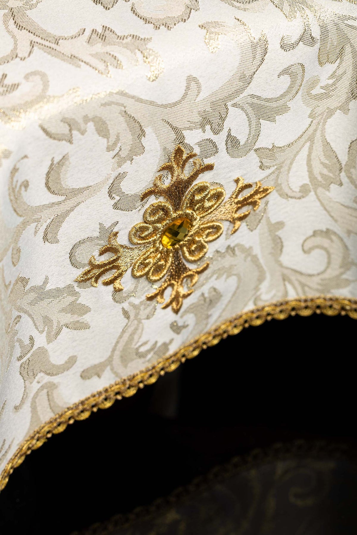 Embroidered chalice veil detail showing cross motif, ecru stone, and scalloped gold edging