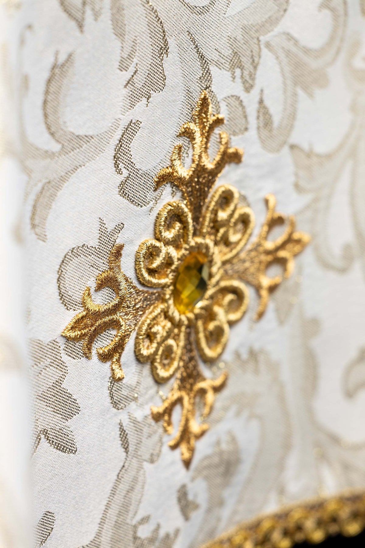 Chalice veil close-up showing gold embroidered cross motif with ecru stone