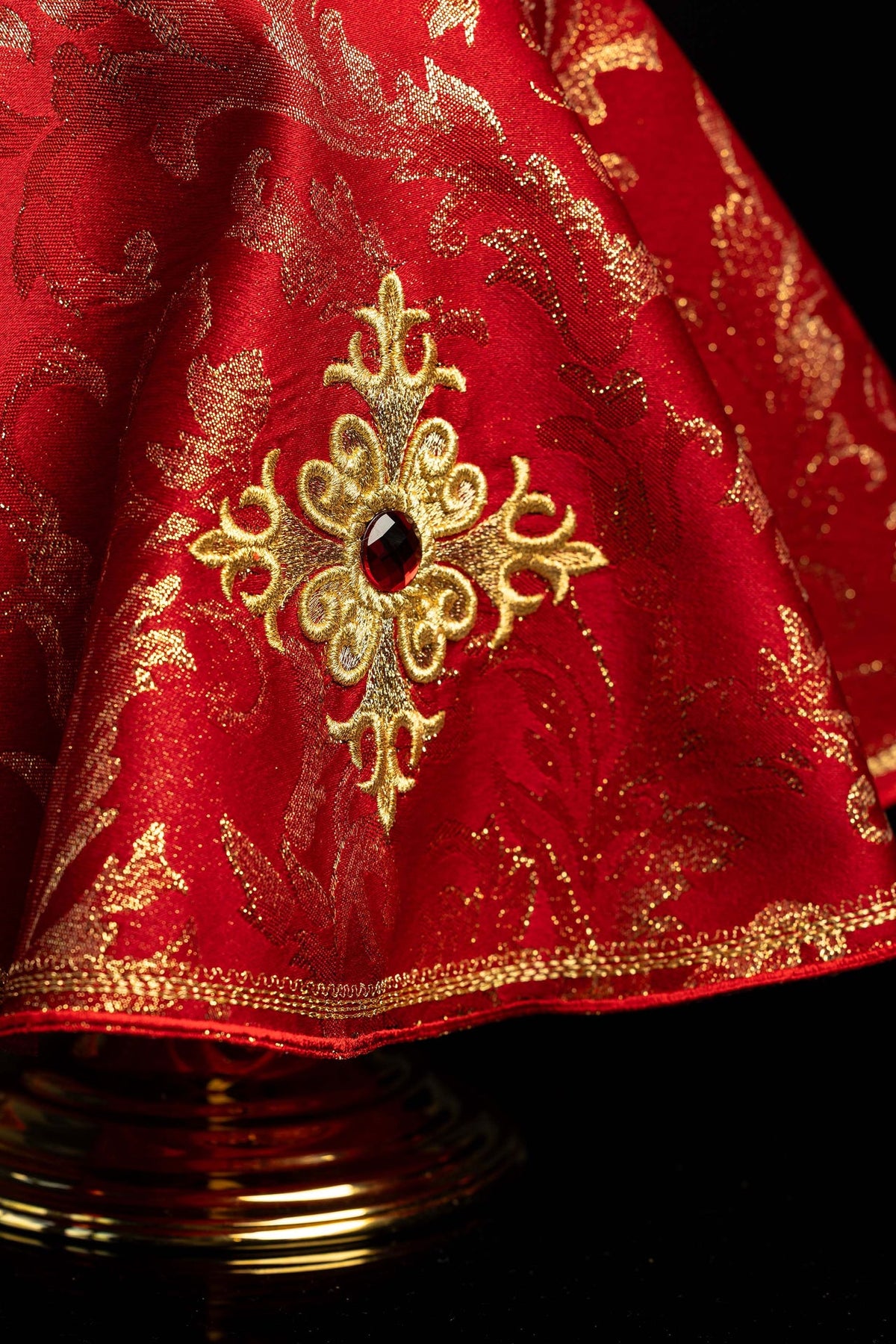 Embroidered cross and central stone detail on the red ciborium veil
