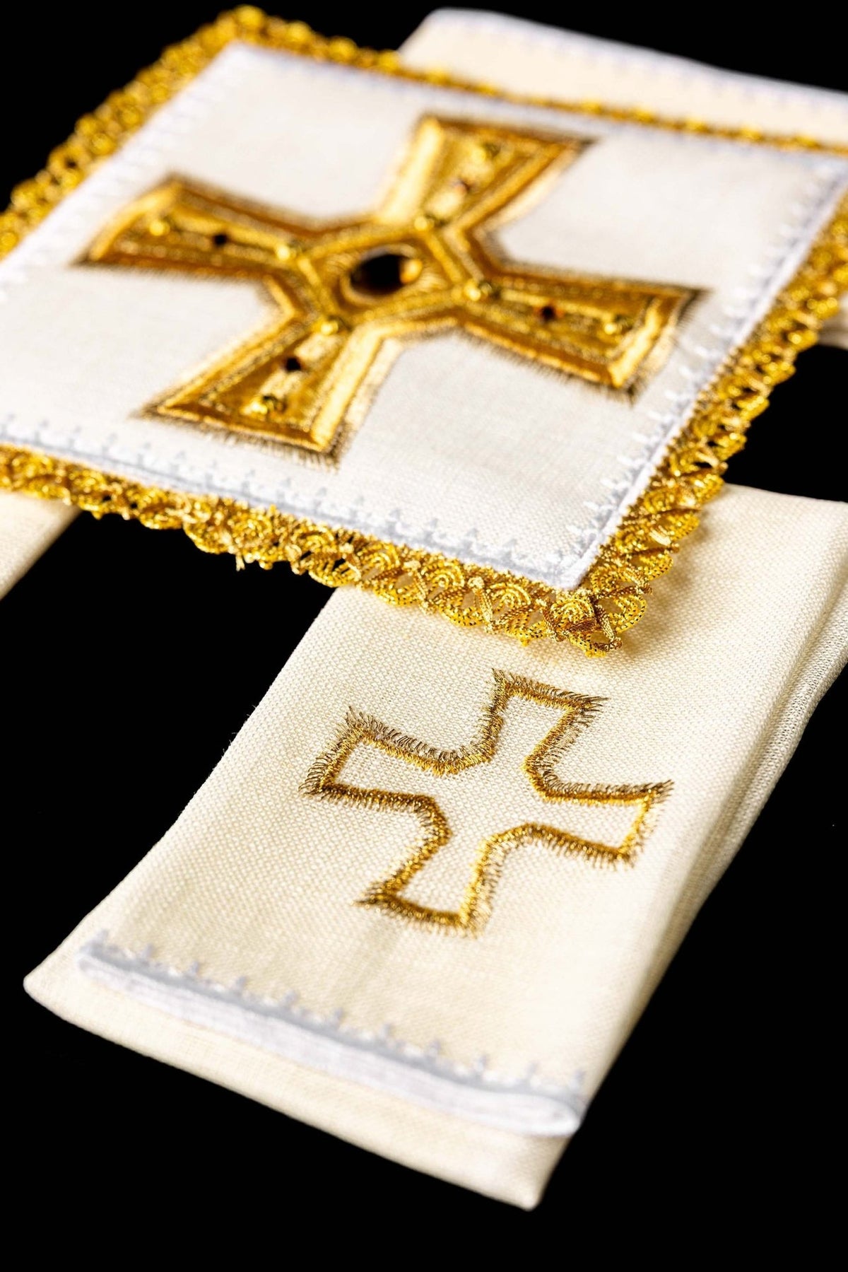 Altar linen set detail showing white fabric, gold trim and embroidered cross