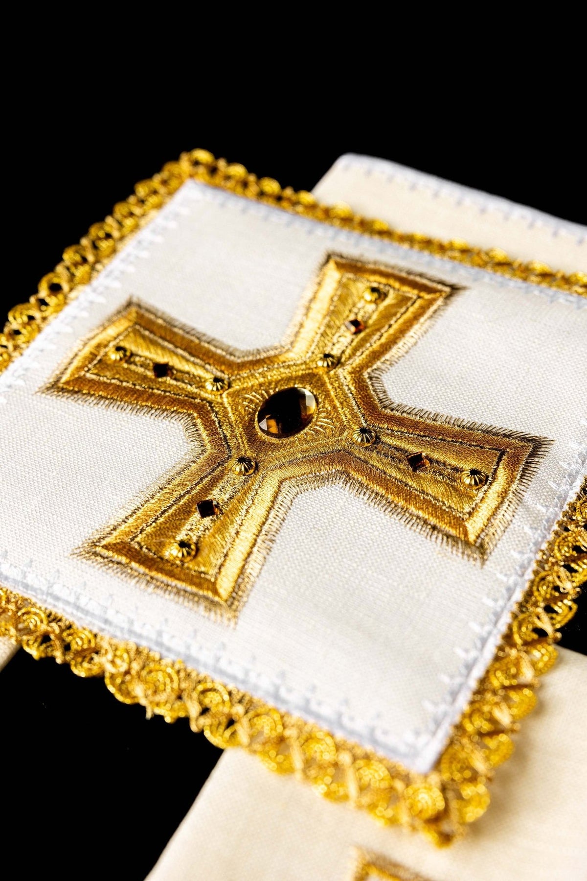 Embroidered altar linen set close-up showing gold cross, stones and decorative edging