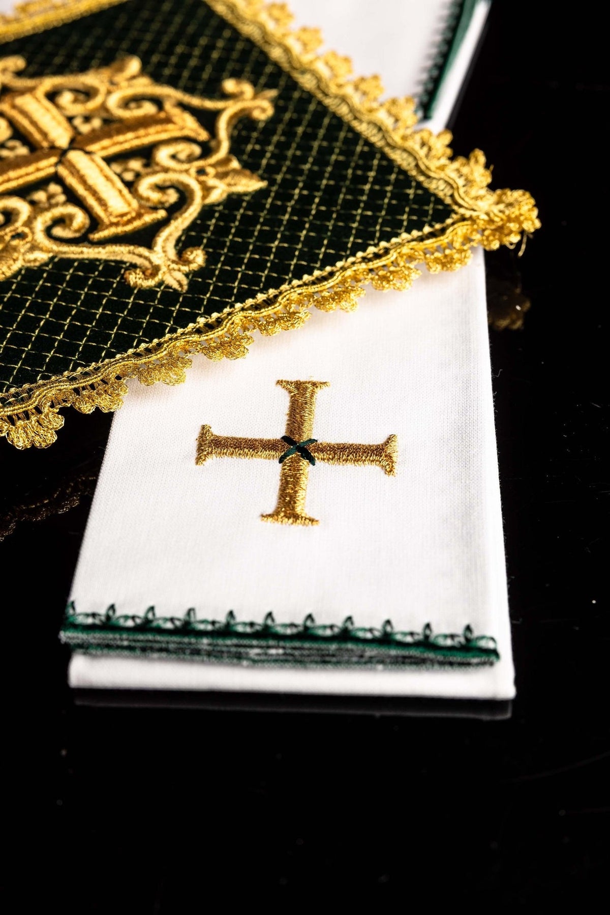 Green velvet chalice pall over white linen with gold embroidered cross and ornate gold trim