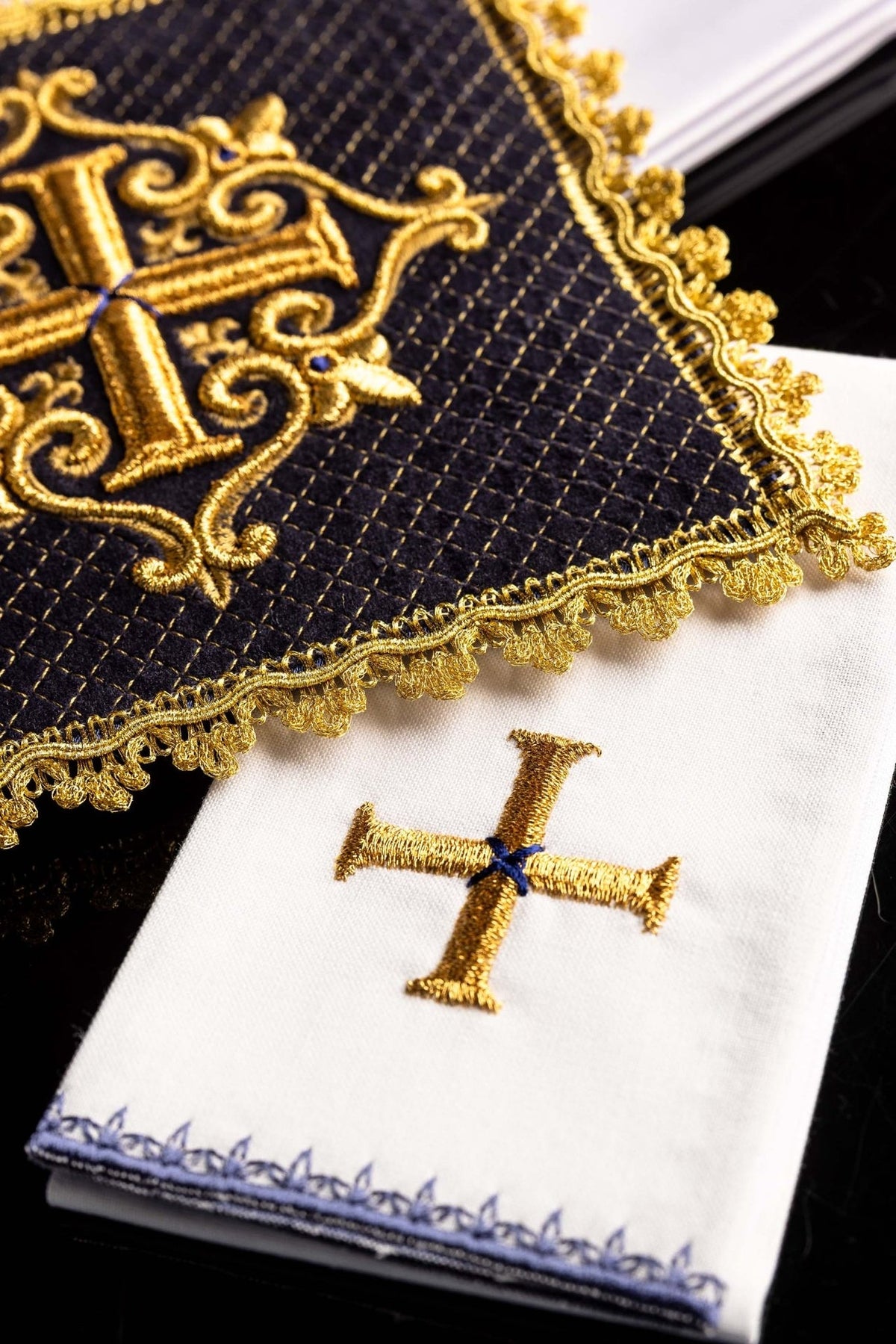 Altar linen set detail showing gold cross embroidery on white linen beside purple velvet panel