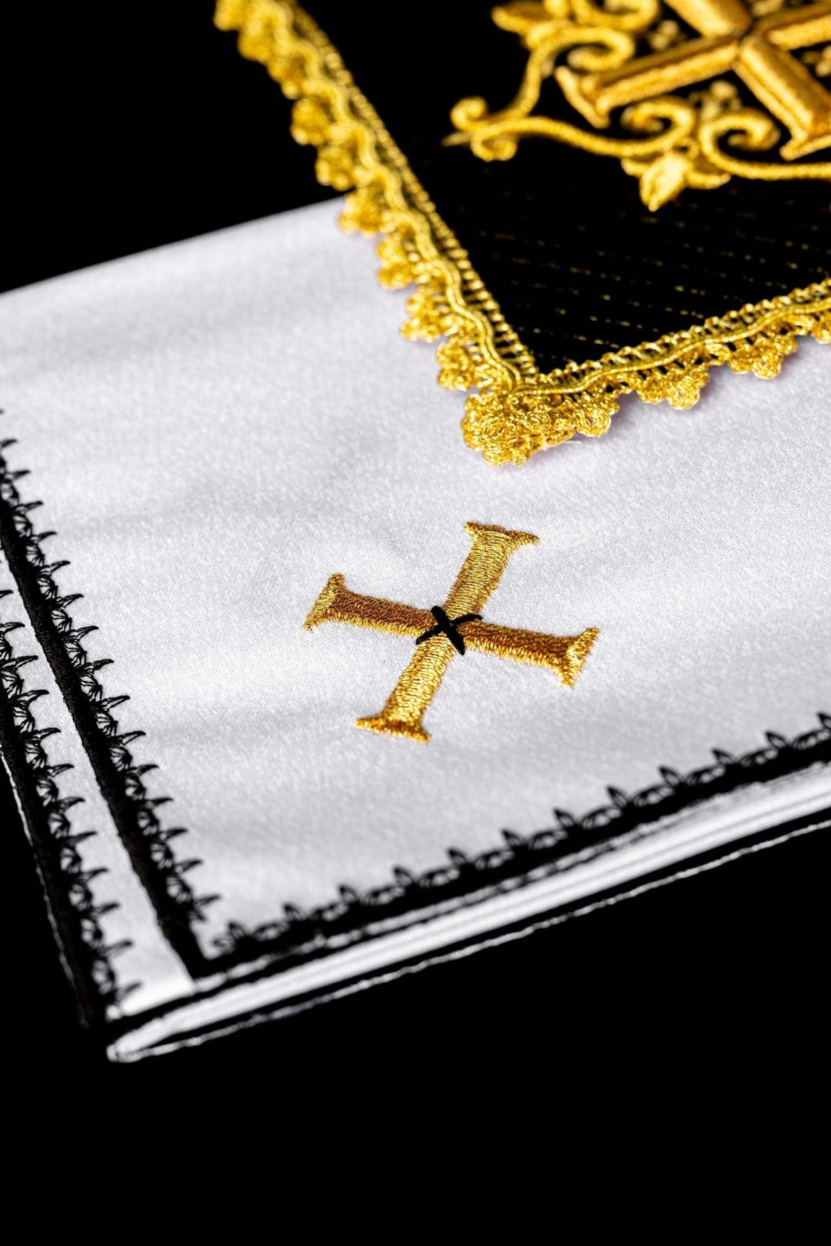 Altar linen set close-up showing gold embroidered cross on white linen with black edging