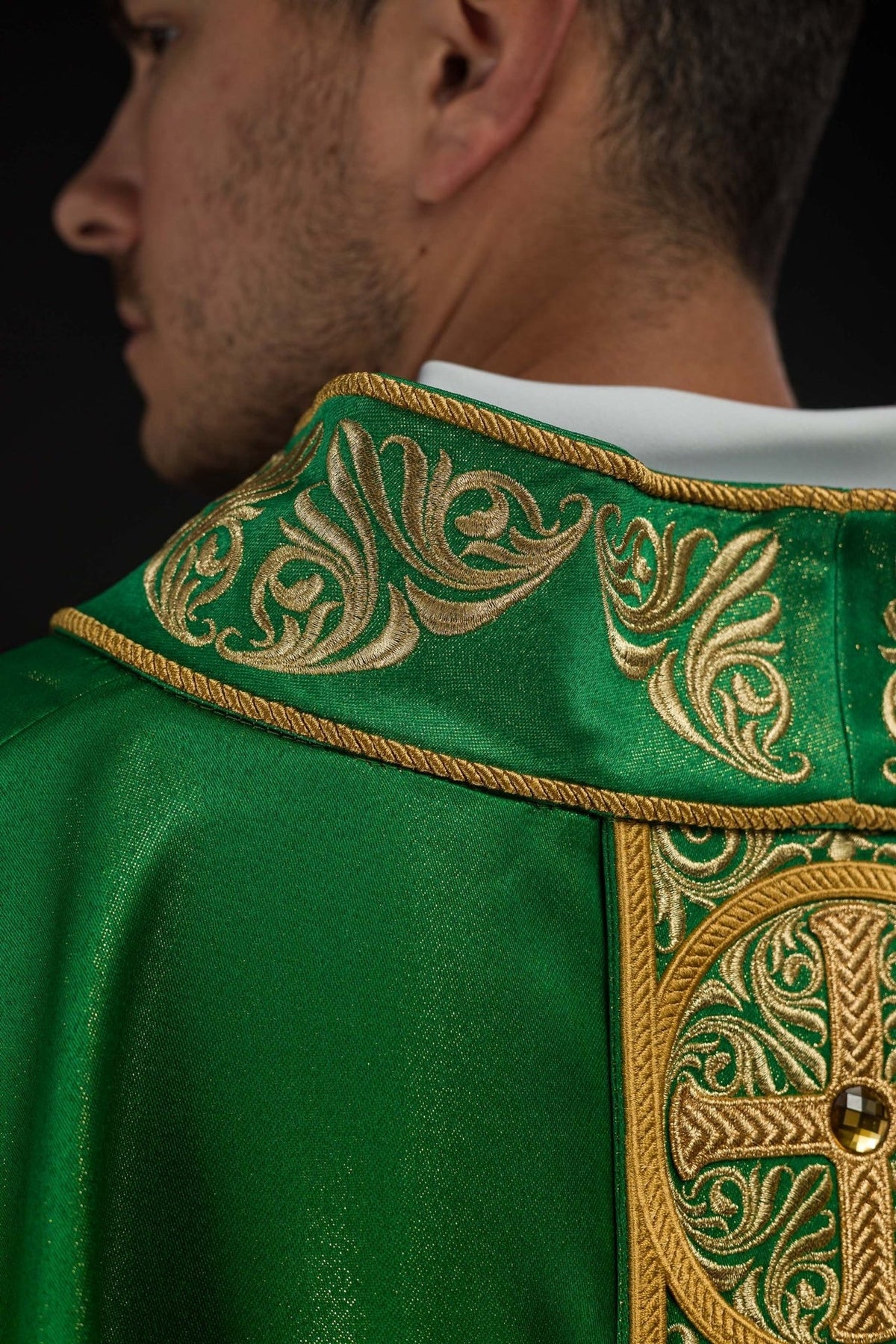 Green chasuble side close-up showing embroidered orphrey and faceted stones