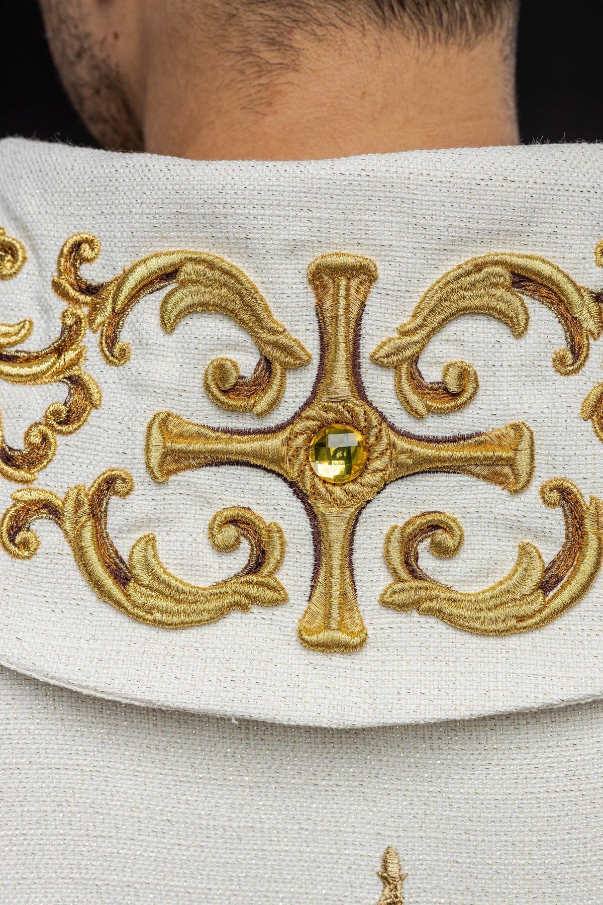 Catholic chasuble, close-up of gold embroidered cross with a central yellow stone