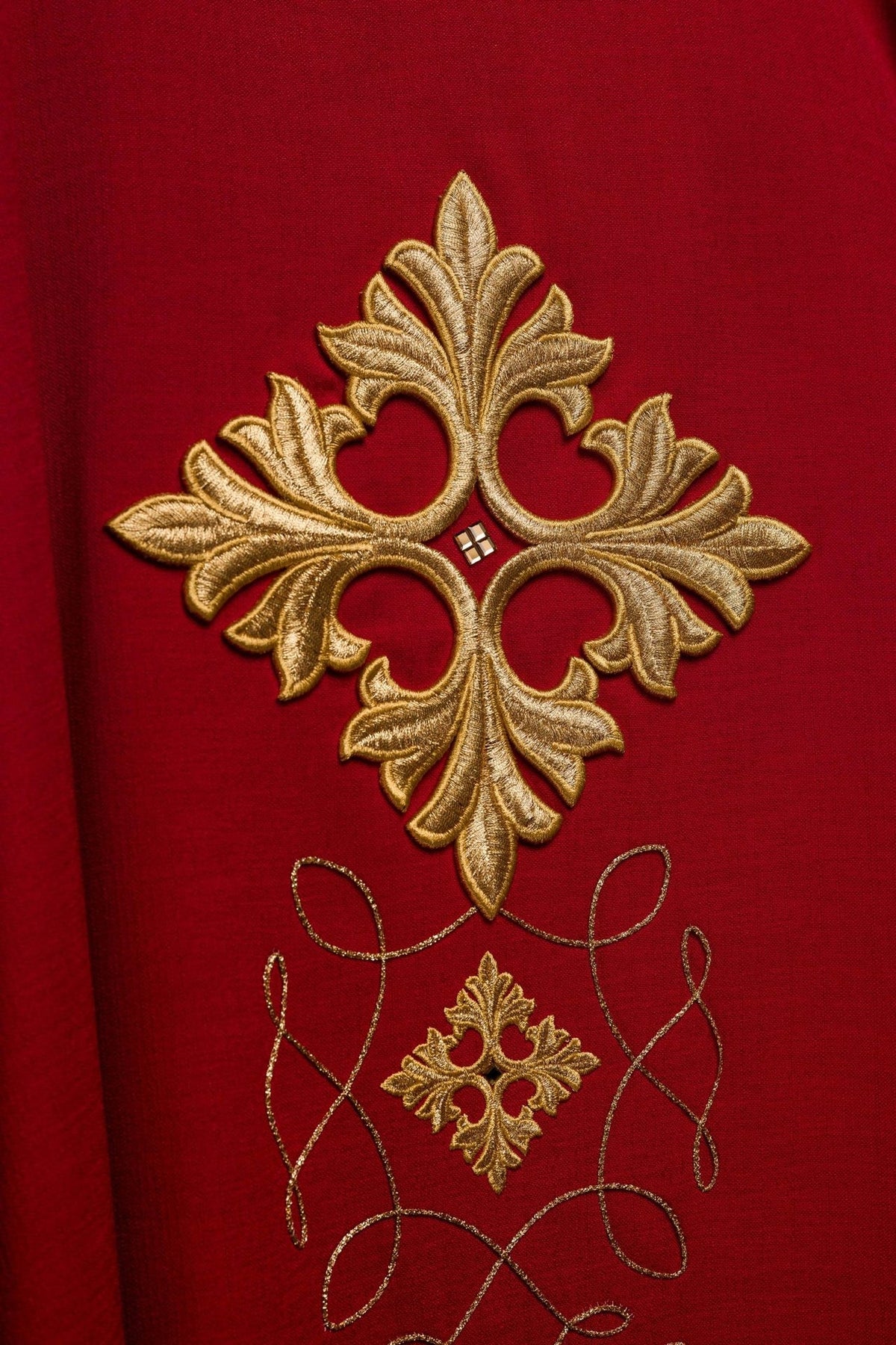 Red chasuble, close-up of gold embroidered cross and smaller ornamental motif