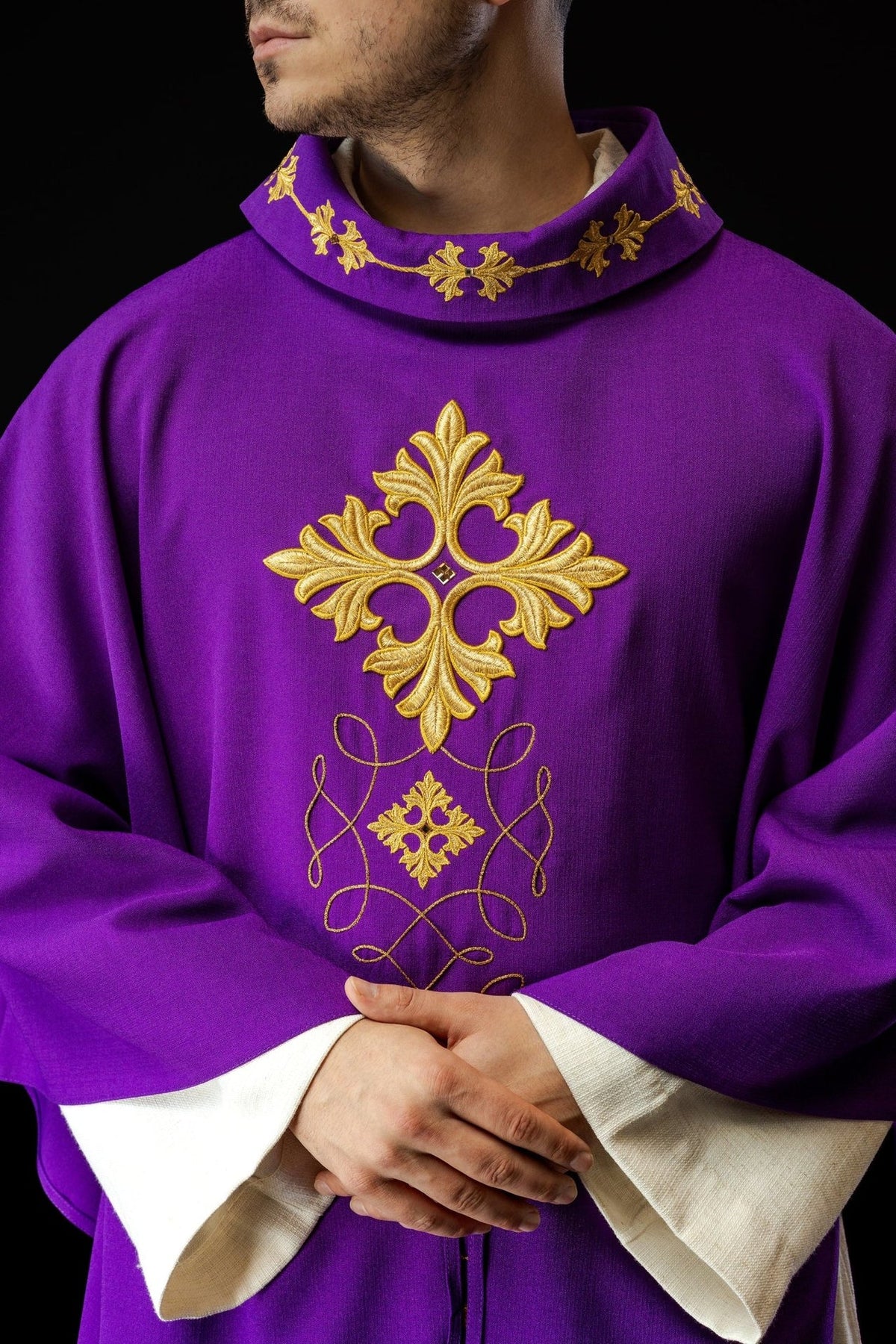 Purple chasuble front close-up with gold embroidered cross and looping cord design