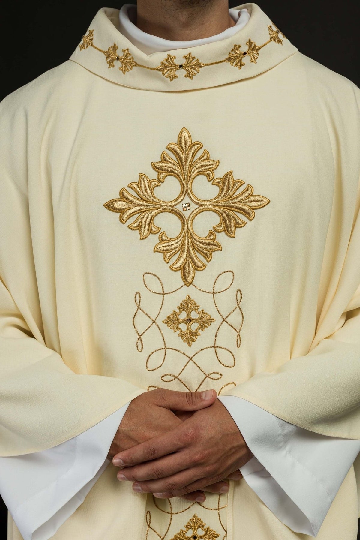 Ivory chasuble close-up showing gold embroidered cross, stand-up collar and scrolling motifs