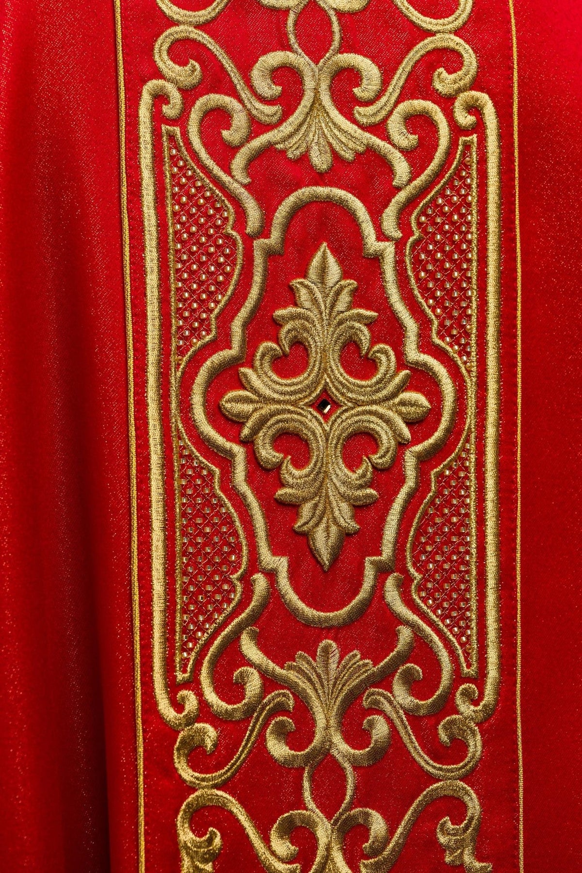 Red chasuble embroidery close-up with ornate gold motifs and textured detailing
