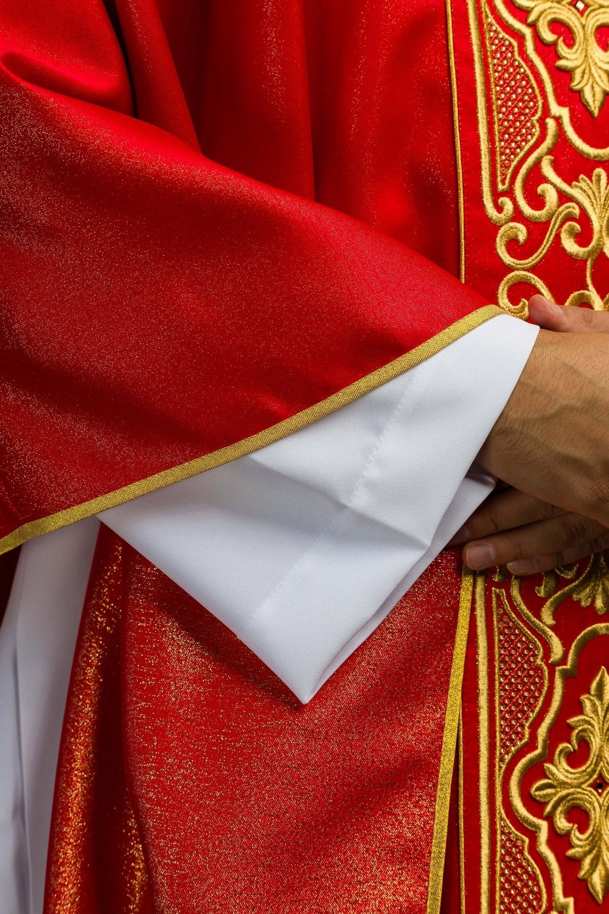 Red chasuble sleeve close-up showing shimmering fabric and gold trim