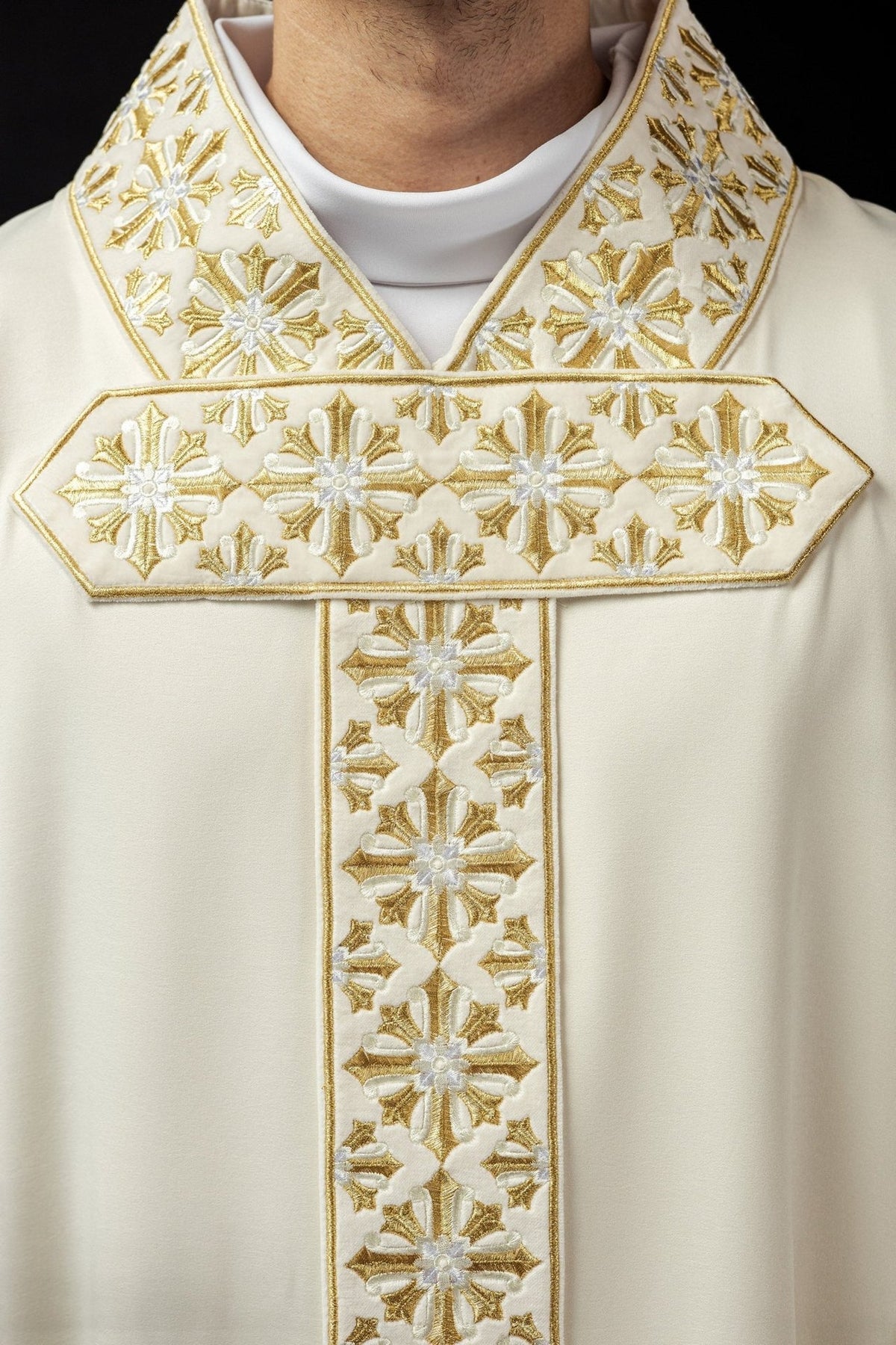 Ecru chasuble close-up showing shimmering gold and white embroidery on the cross and collar