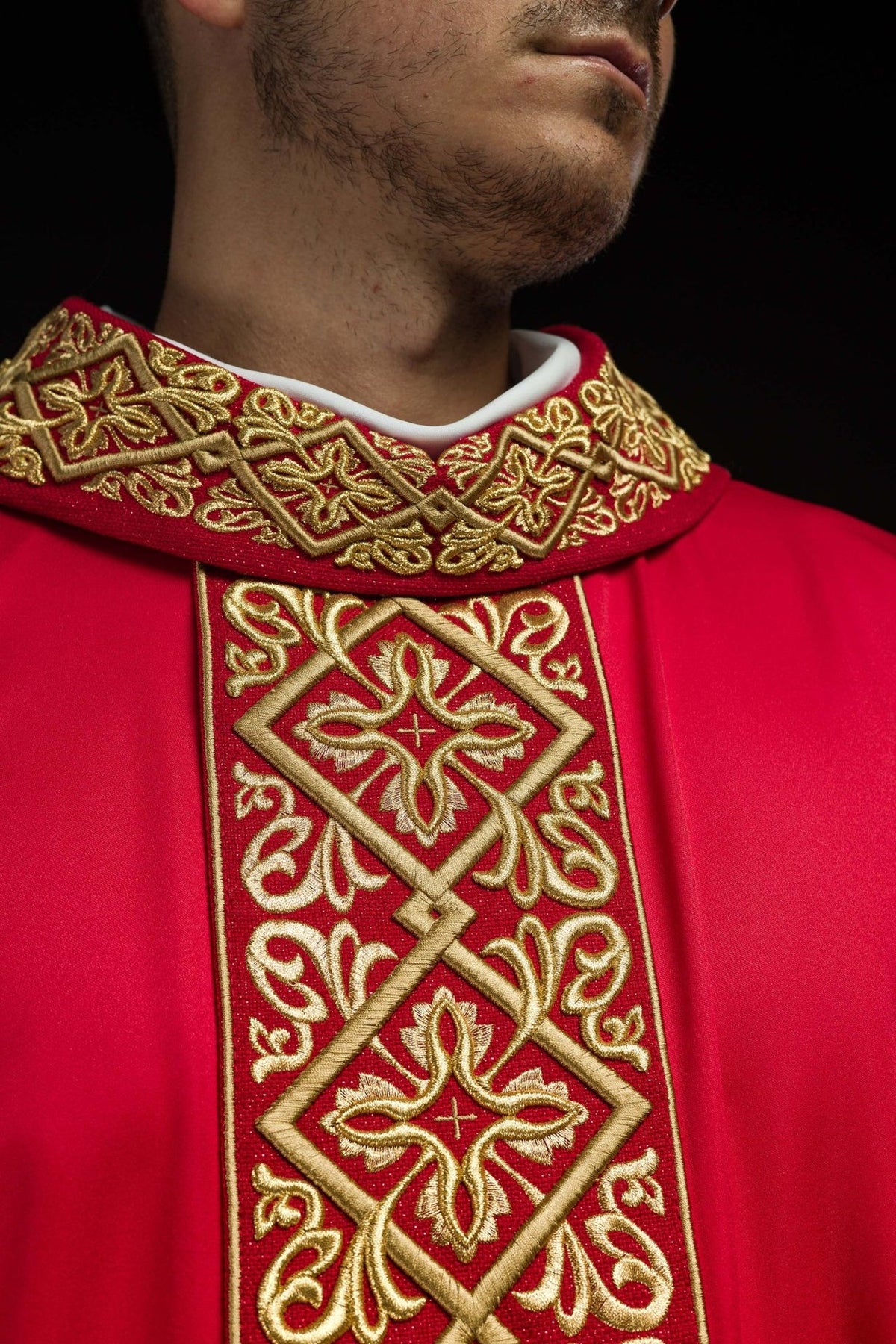 Red chasuble close-up showing embroidered gold stand-up collar and front cross motifs