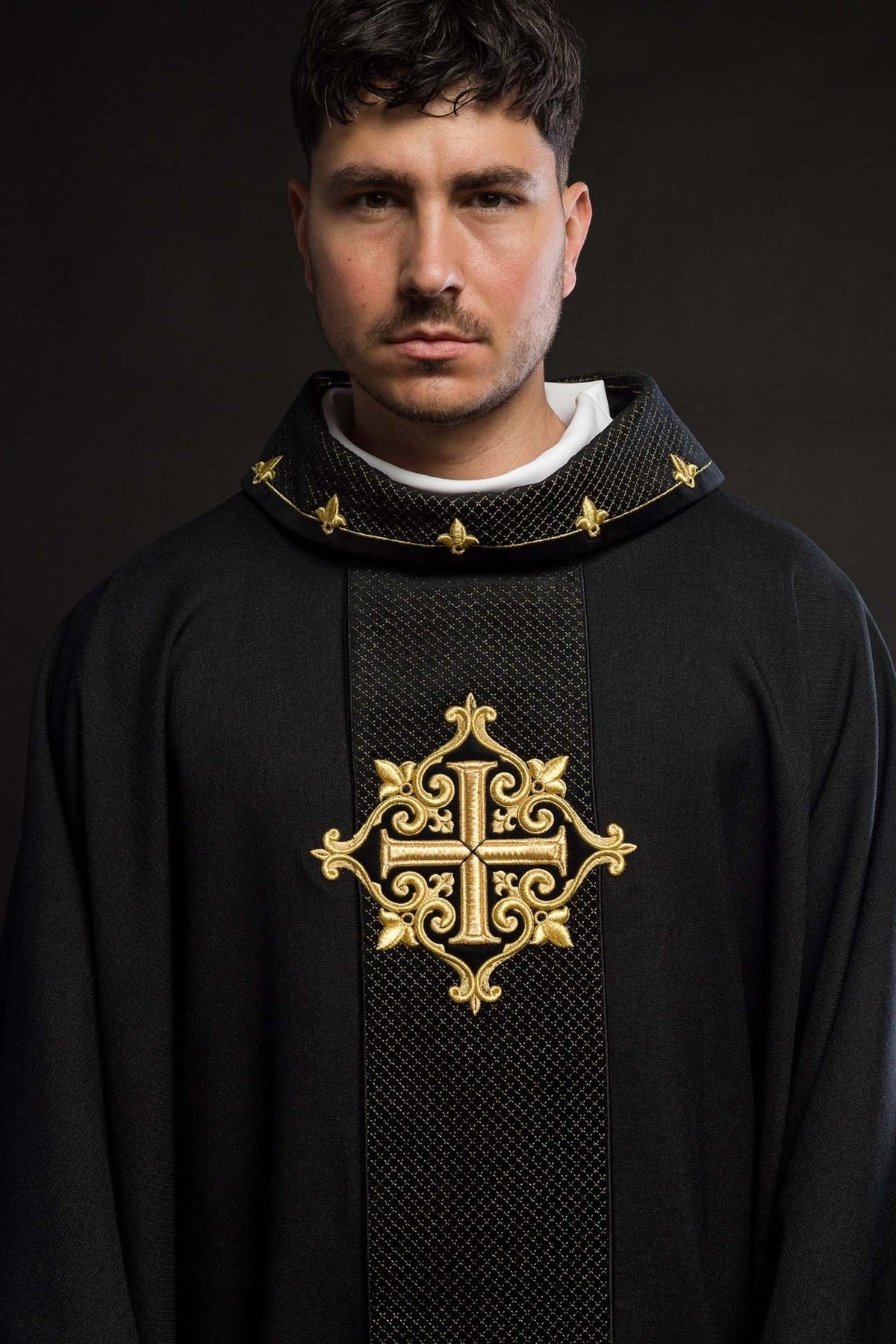 Black chasuble close-up with gold cross embroidery, stand-up collar and diamond-patterned trim