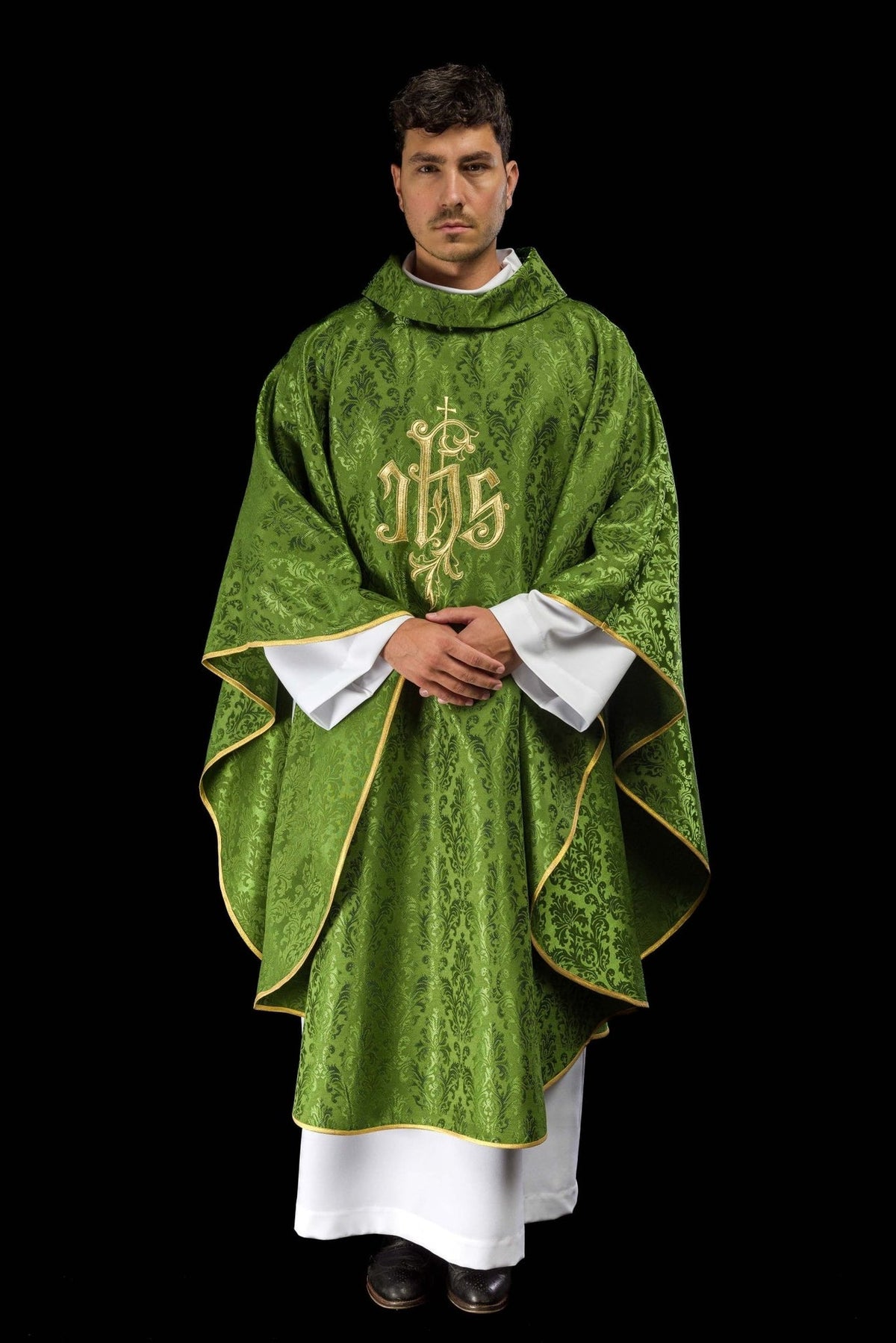 Green chasuble front view showing flowing shape, gold trim and embroidered IHS motif