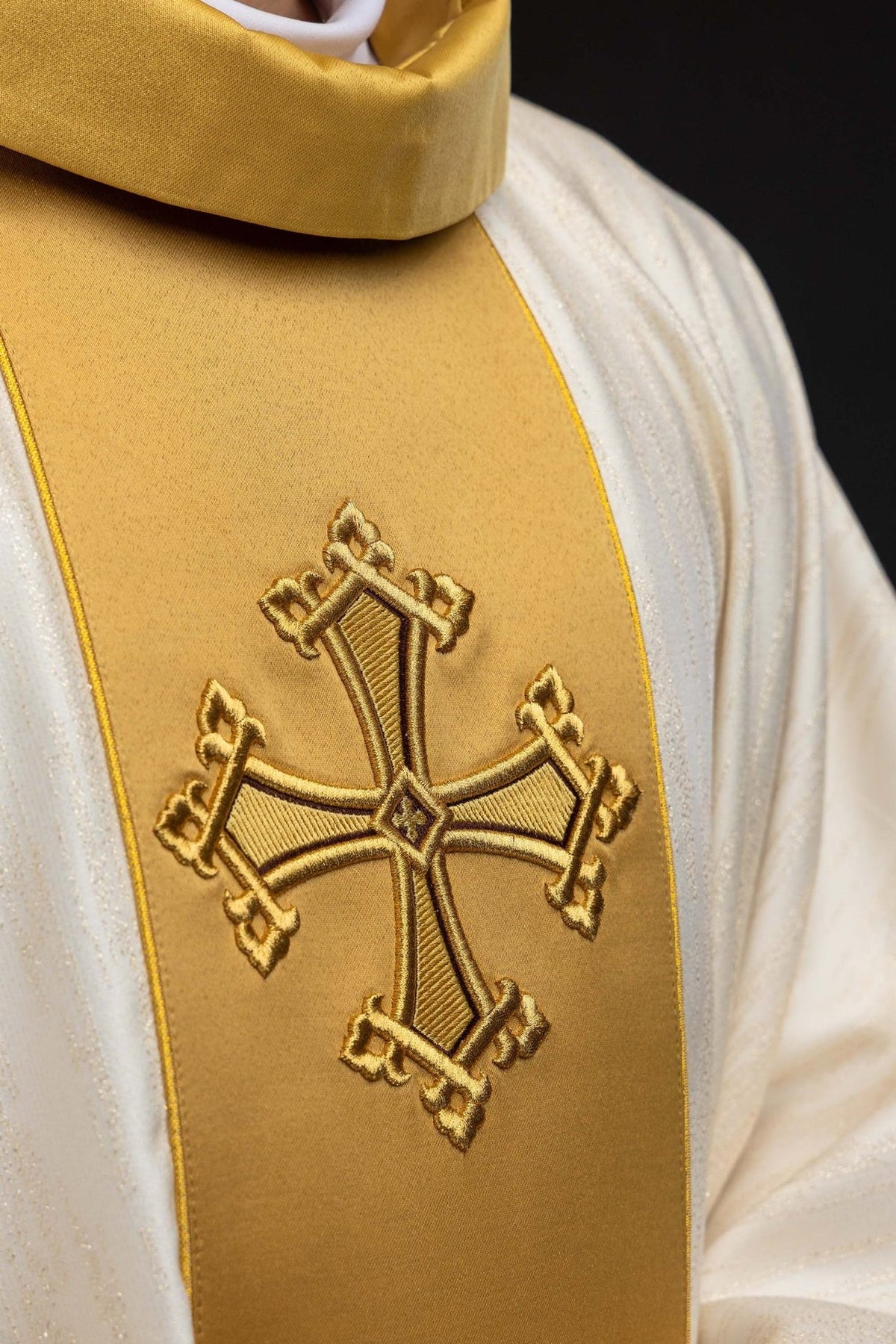 Ecru chasuble close-up showing gold embroidered cross on the orphrey