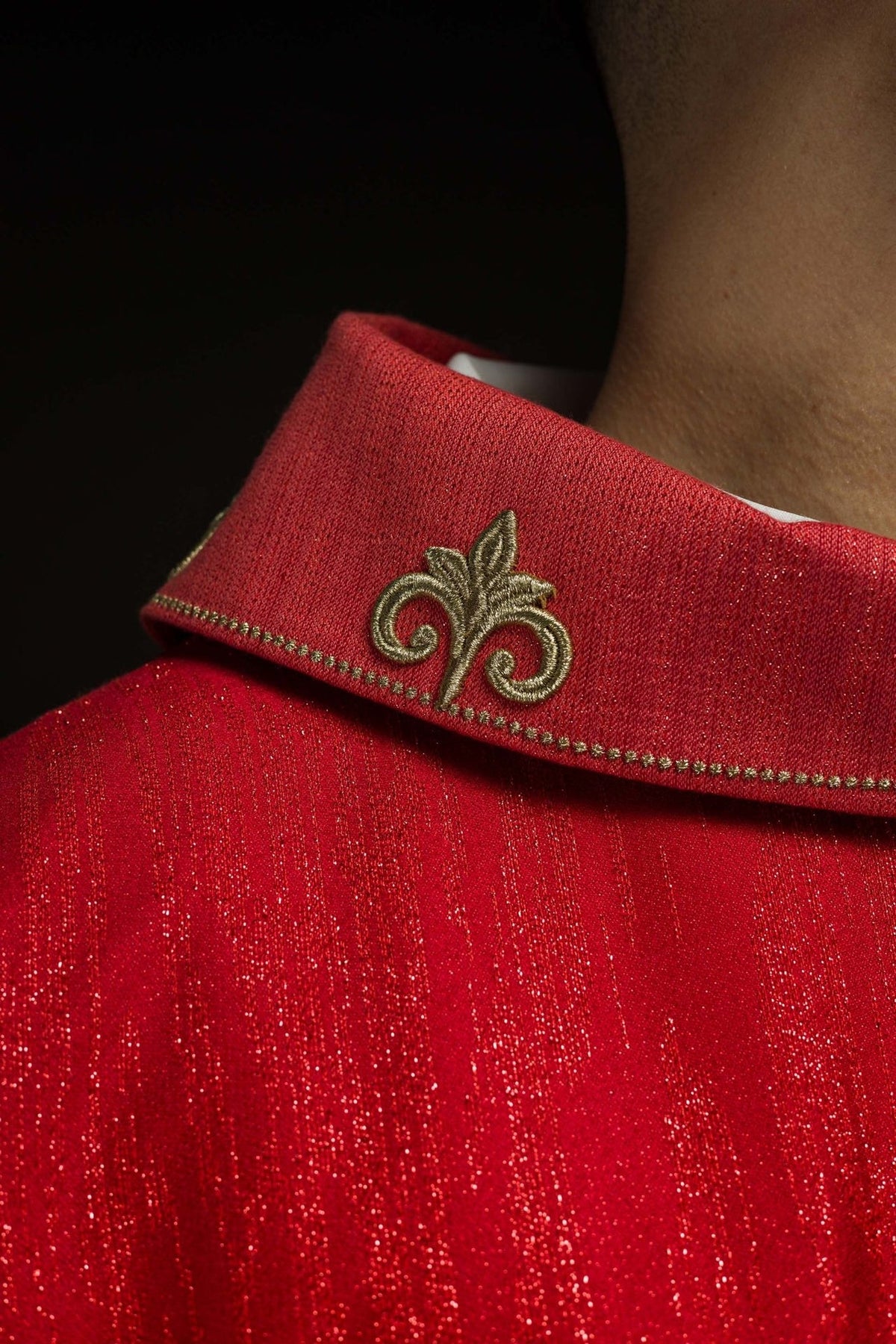 Red chasuble sleeve and front detail with embroidered cross and white cuffs
