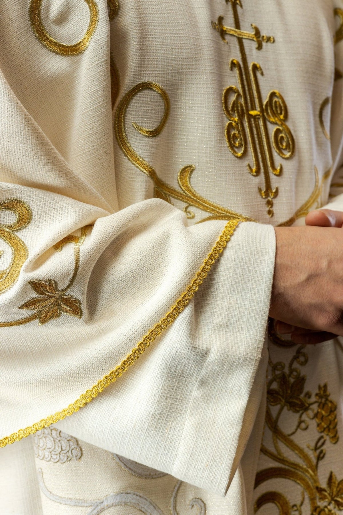 Ecru chasuble close-up showing woven fabric and gold embroidery