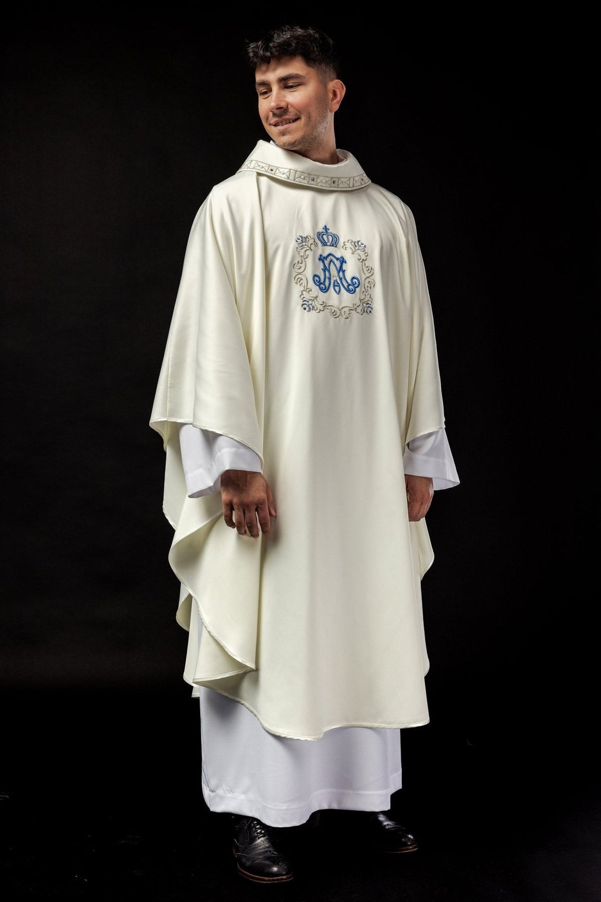 Marian chasuble worn front view, showing ivory fabric, blue monogram and gold embroidery