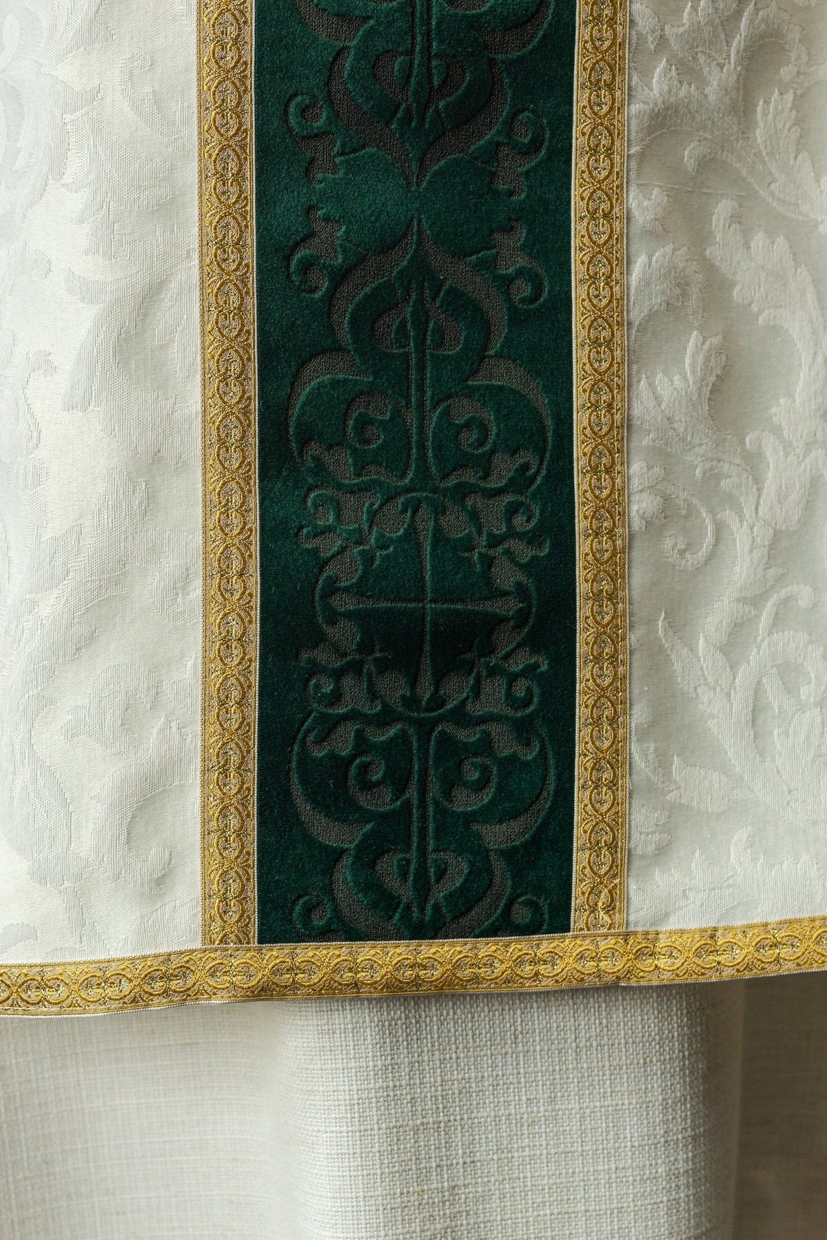 Green velvet orphrey close-up with dark motifs and gold embroidered cross