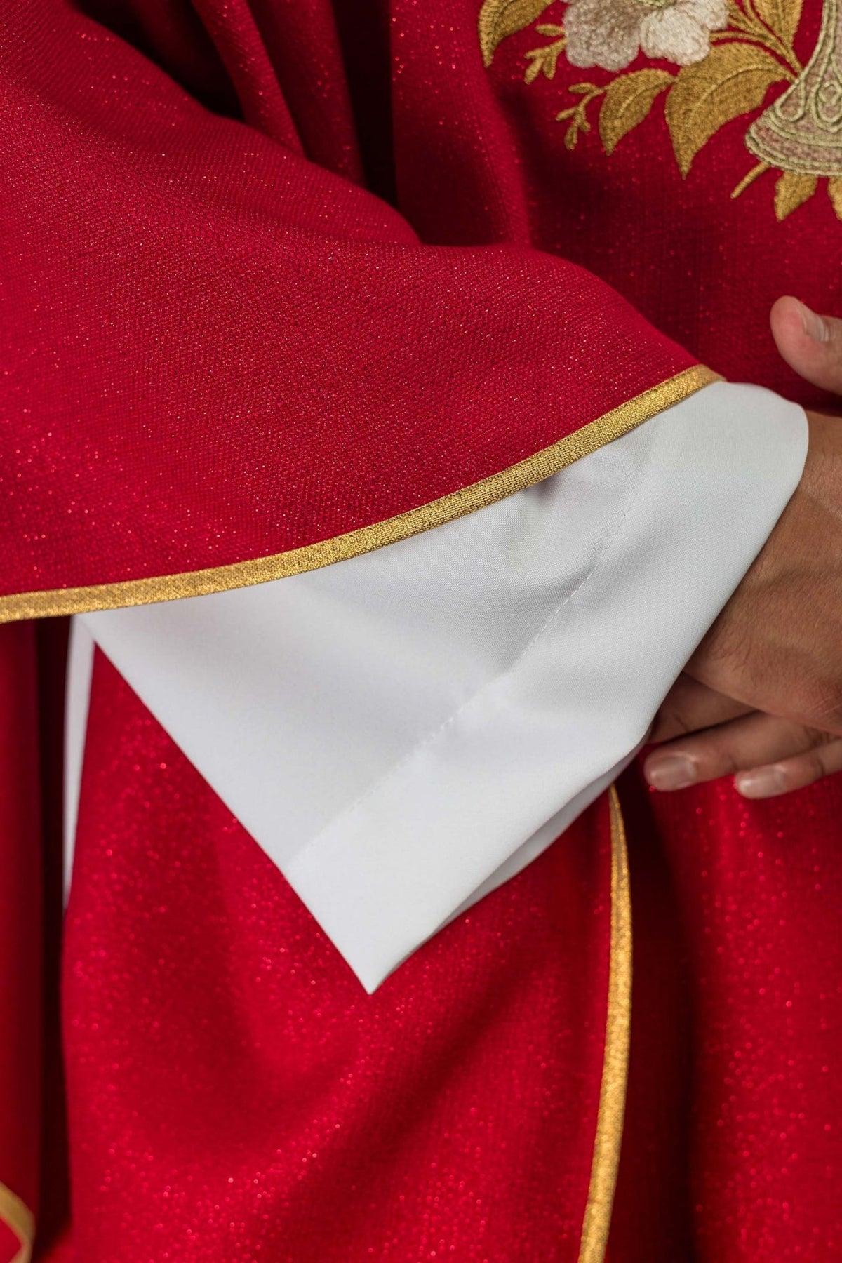Red chasuble close-up showing red fabric and gold trim at the sleeve