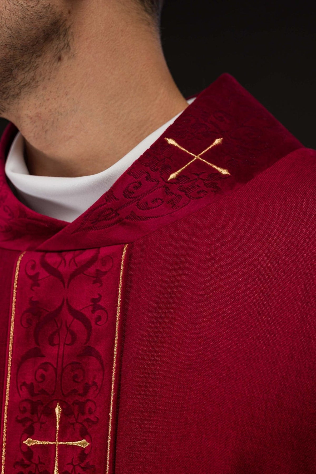 Red chasuble collar close-up with gold cross and dark embroidery