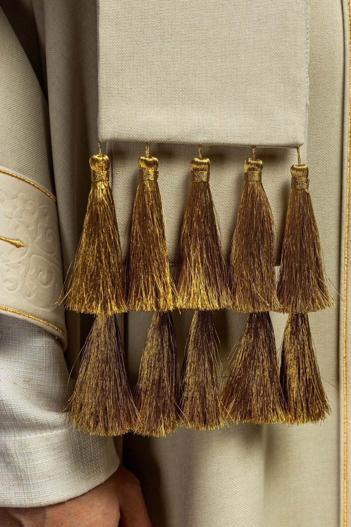 Ecru chasuble detail showing rows of gold tassels beside the embroidered orphrey