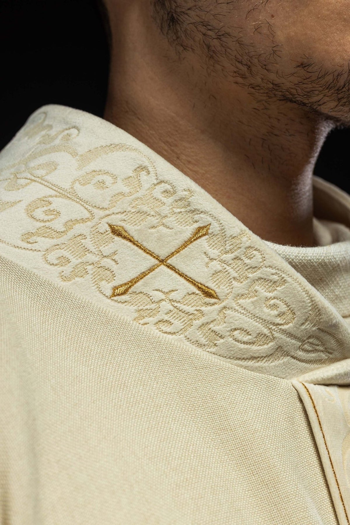 Ecru chasuble collar close-up with an embroidered gold cross and scrolling embroidery