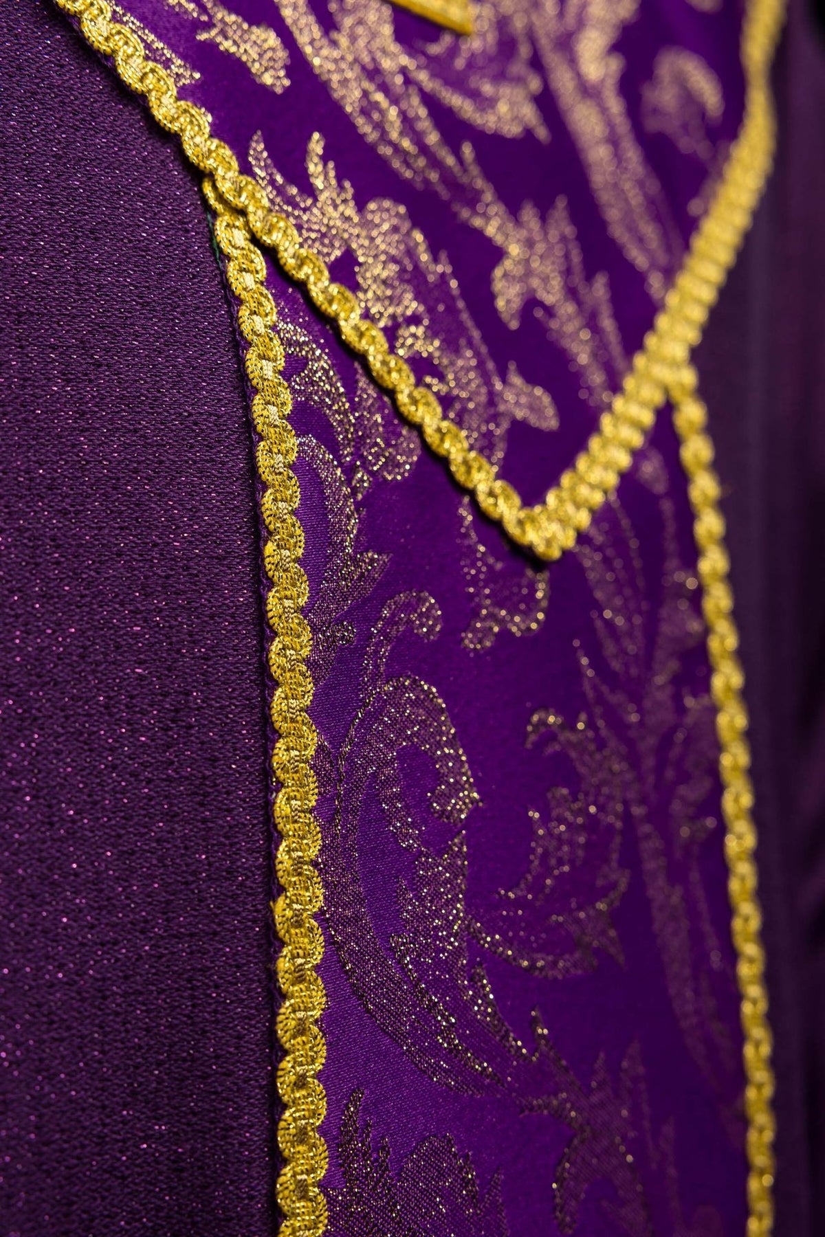 Purple chasuble detail showing gold edging and jacquard fabric