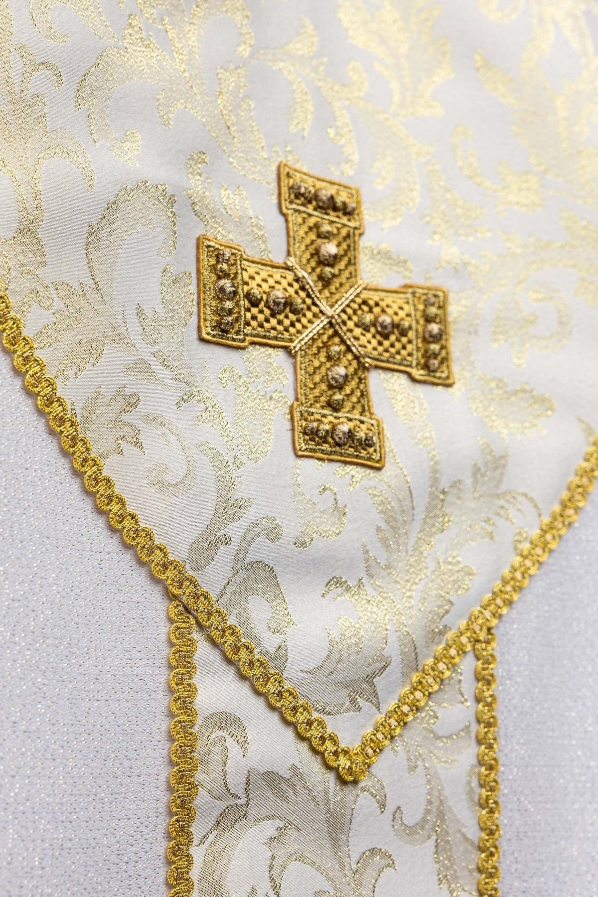 Ecru chasuble close-up showing gold cross and floral jacquard